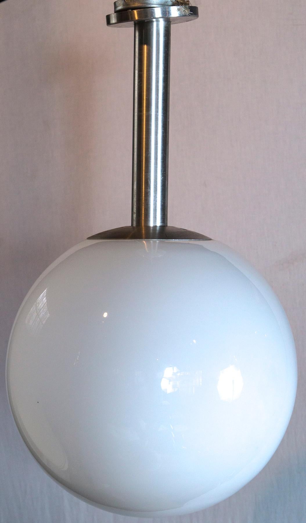 White glass globe pendant light with an aluminum stem. It accommodates one standard bulb.
Two pendant lights are available. Priced individually.