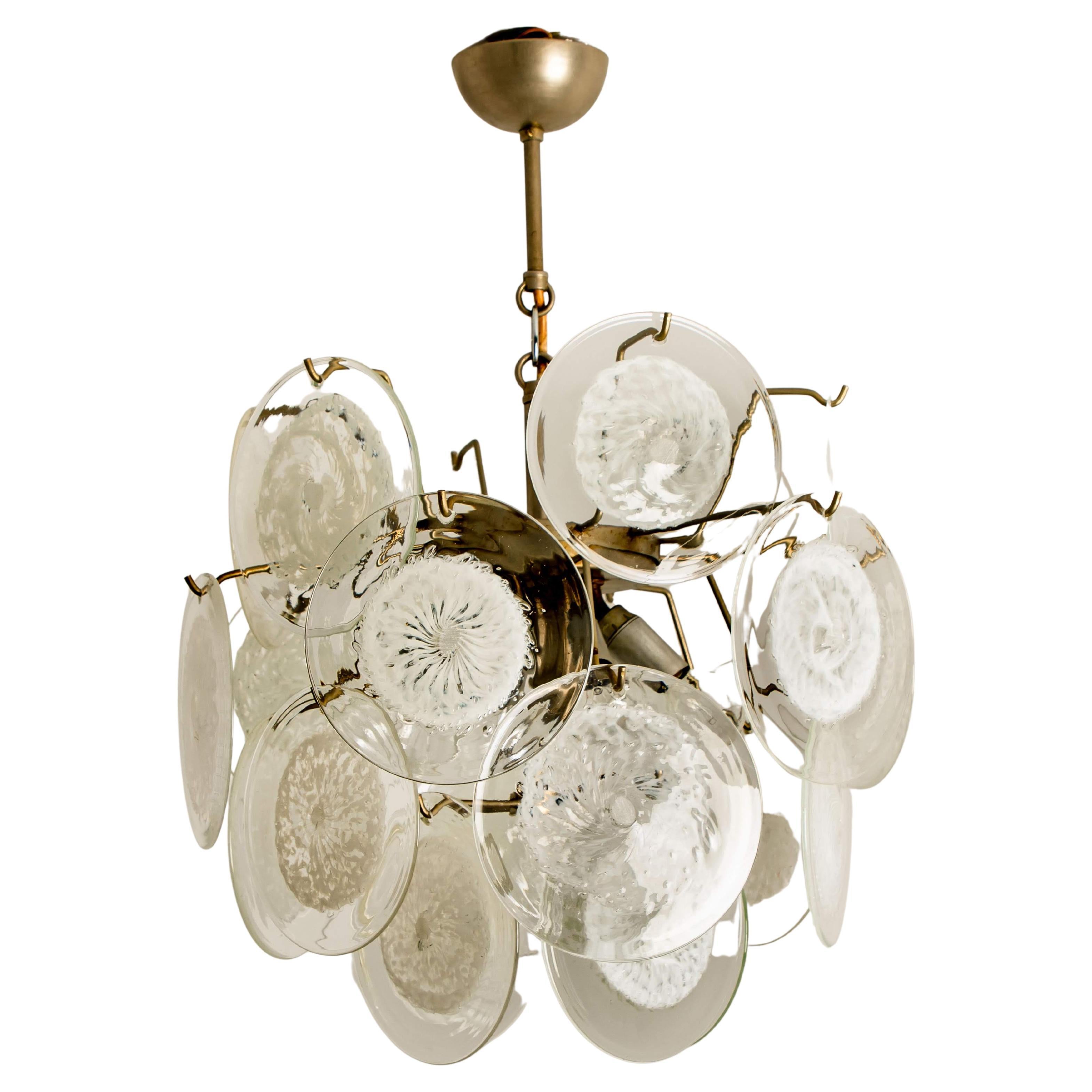 A gorgeous four tiers hanging light fixture, attributed to Vistosi, Italy, manufactured in circa 1970 (late 1960s and early 1970s). With graduated tiers of smoked round facet chaped glass discs framed by half moon shaped brass. The chandelier is