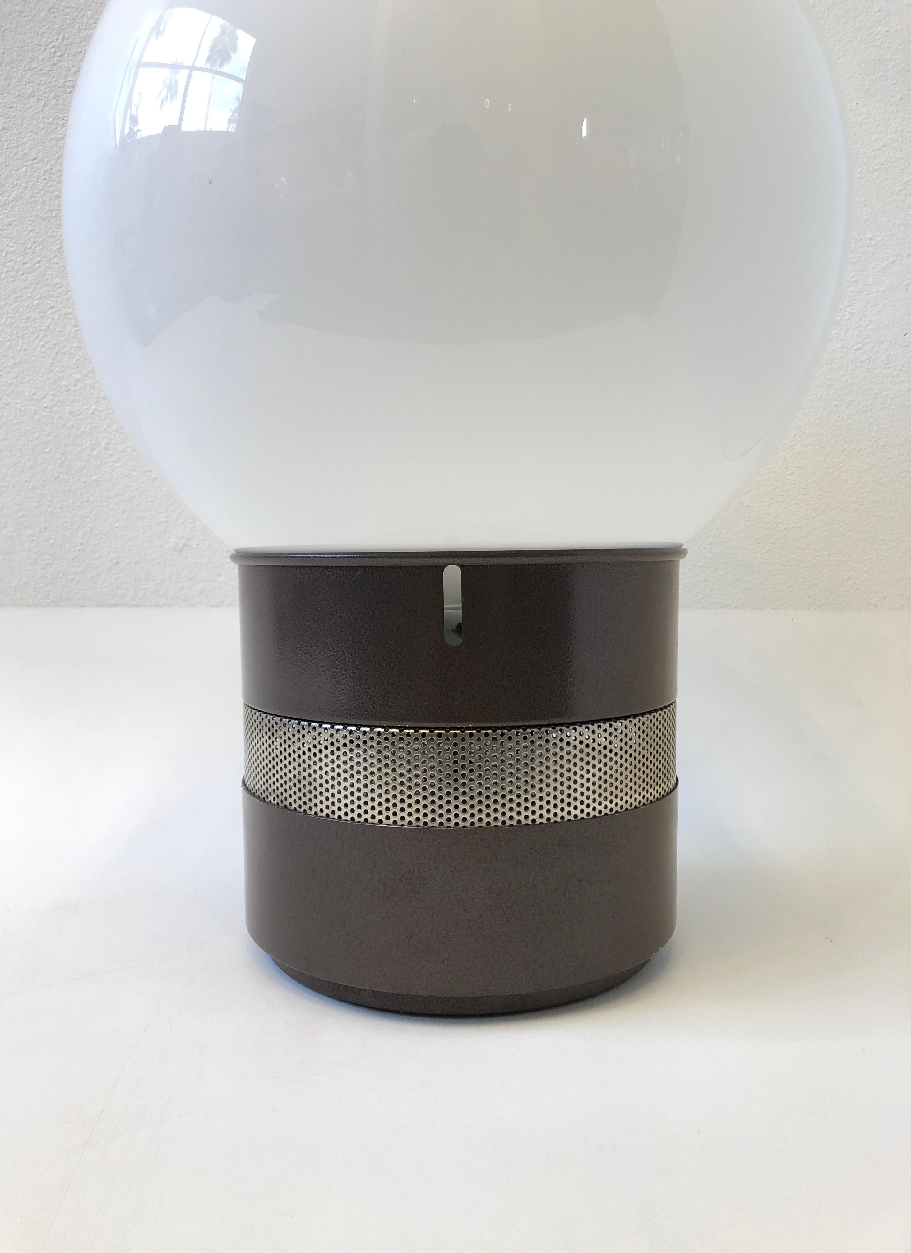 1970’s “Mezzoracolo” table lamp by renowned Italian Architect Gae Aulenti. 
The lamp is constructed of steel that’s powder coated brown and the shade is hand blown white glass globe. 
It takes one regular Edison lightbulb 75w max and two small