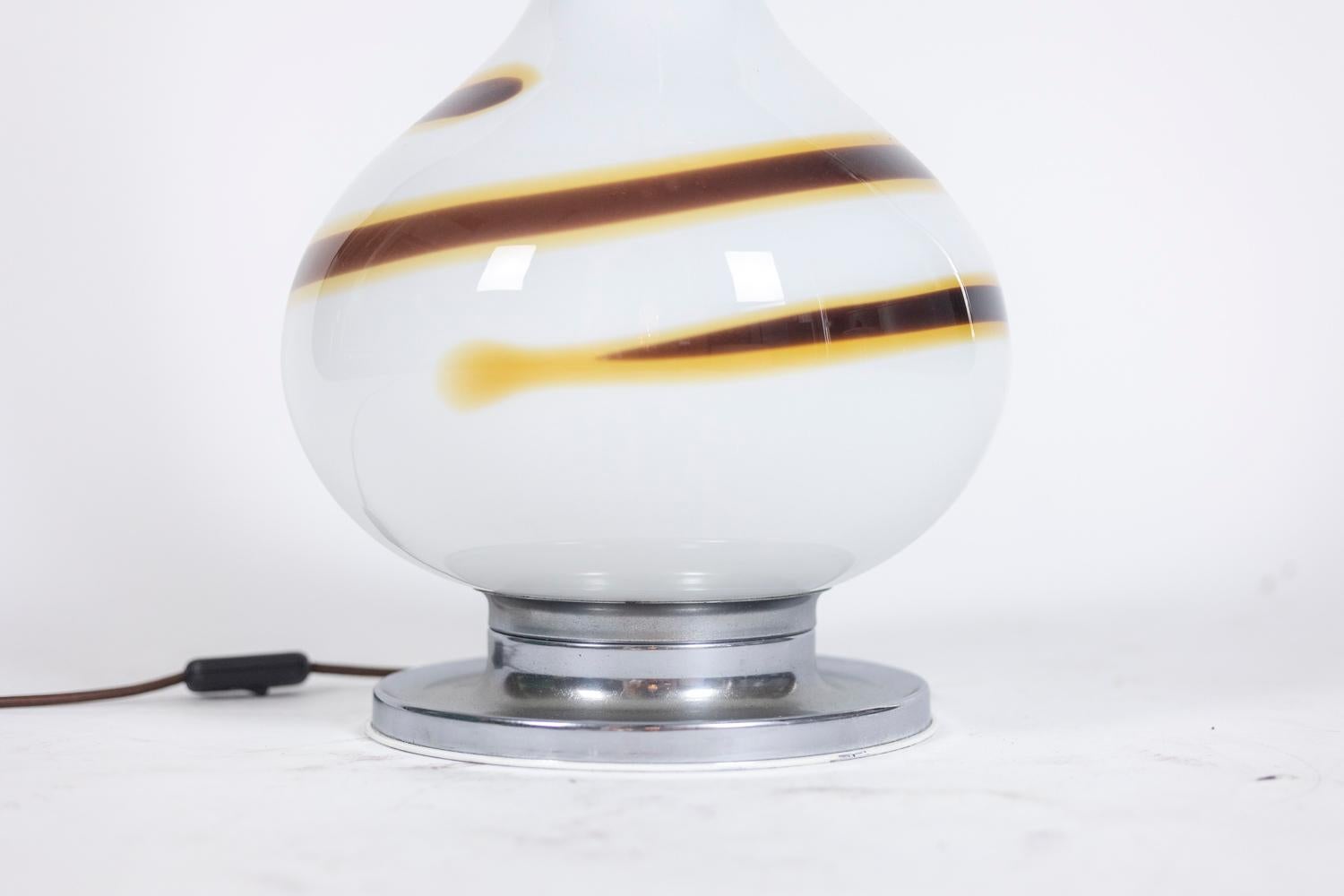White glass lamp decorated with a brown and yellow spiral, baluster shape. Base and top of the lamp in chromed metal.

Italian work made in the 1970s.
