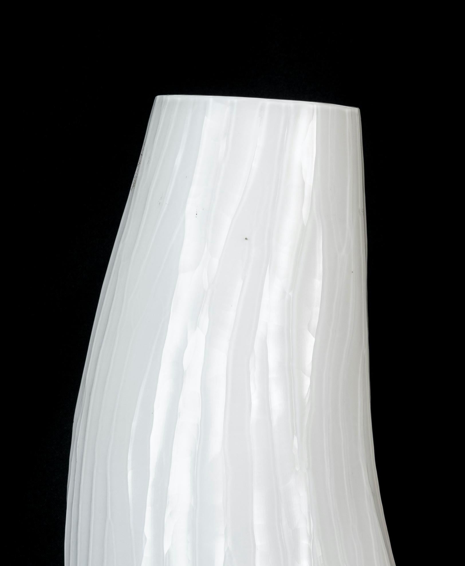 Die Vase aus weißem Glas ist ein wunderschönes Dekorationsobjekt aus Glas, das in den 1970er Jahren hergestellt wurde. 

Sehr schöne Glasvase mit einer sinusförmigen Form. Die Vase hat eine besondere Glasbearbeitung, die 
das macht sie