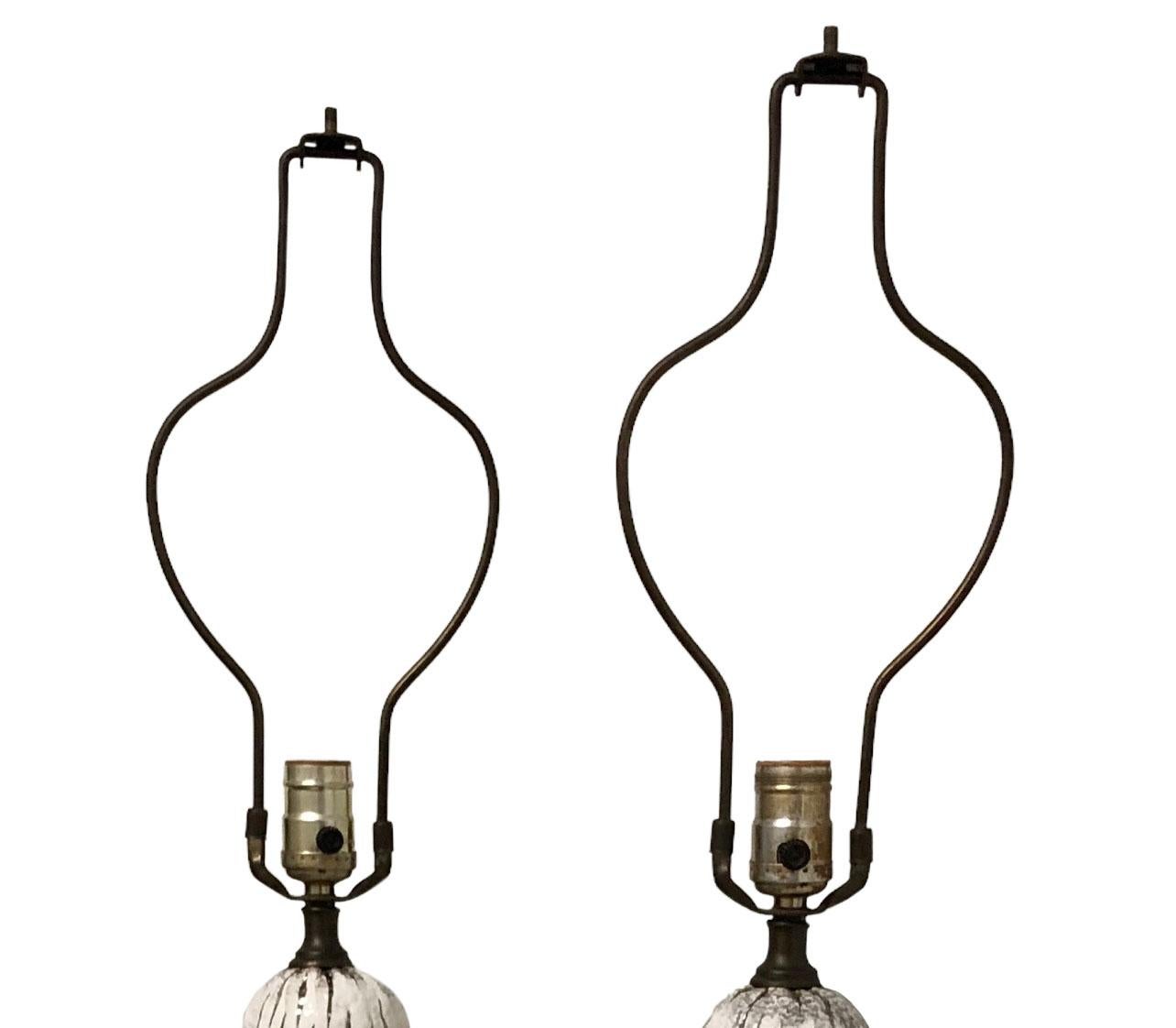 A pair of circa 1950s maybe earlier, Hollywood Regency, white glazed Italian fiancé with silver luster lamps. They have a patina bronze base and original harps. Lamps are in good working condition for the age.