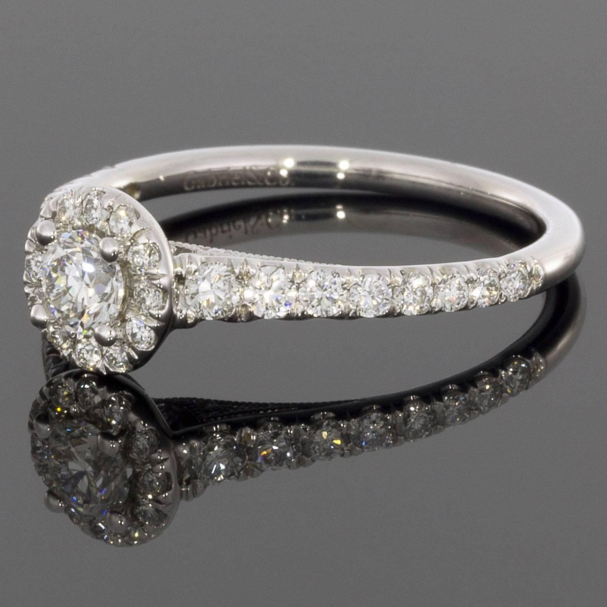 This beautiful diamond engagement ring features a 0.24 carat round diamond center stone and has a total carat weight of 0.87 including accent stones with a color and clarity grade of G-H/SI. The round center stone is prong set in a 14 karat white