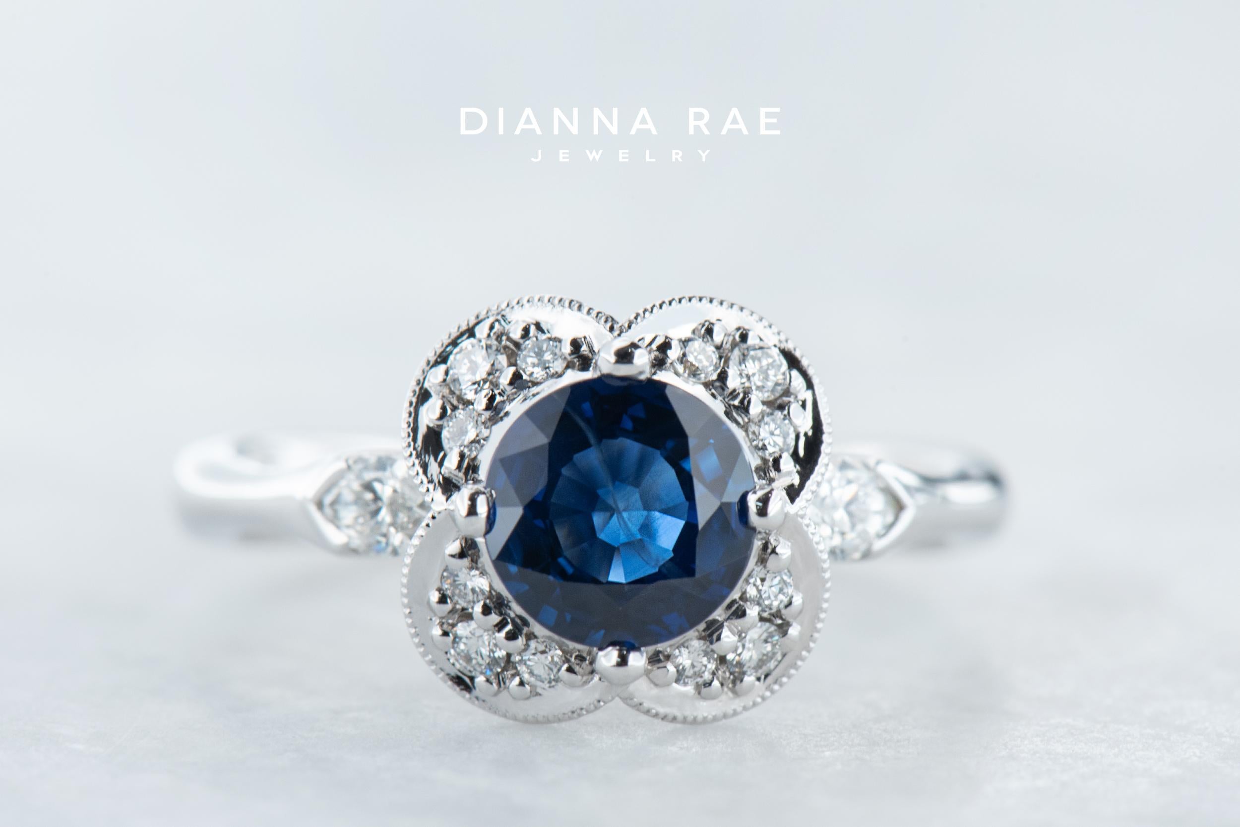 Simply whimsical, this sapphire and diamond floral ring features a sparkling scalloped halo. Two marquise-cut diamonds lay on either side of the band giving it the perfect added sparkle. Created in 14k white gold, this 1.20ct. round bright blue