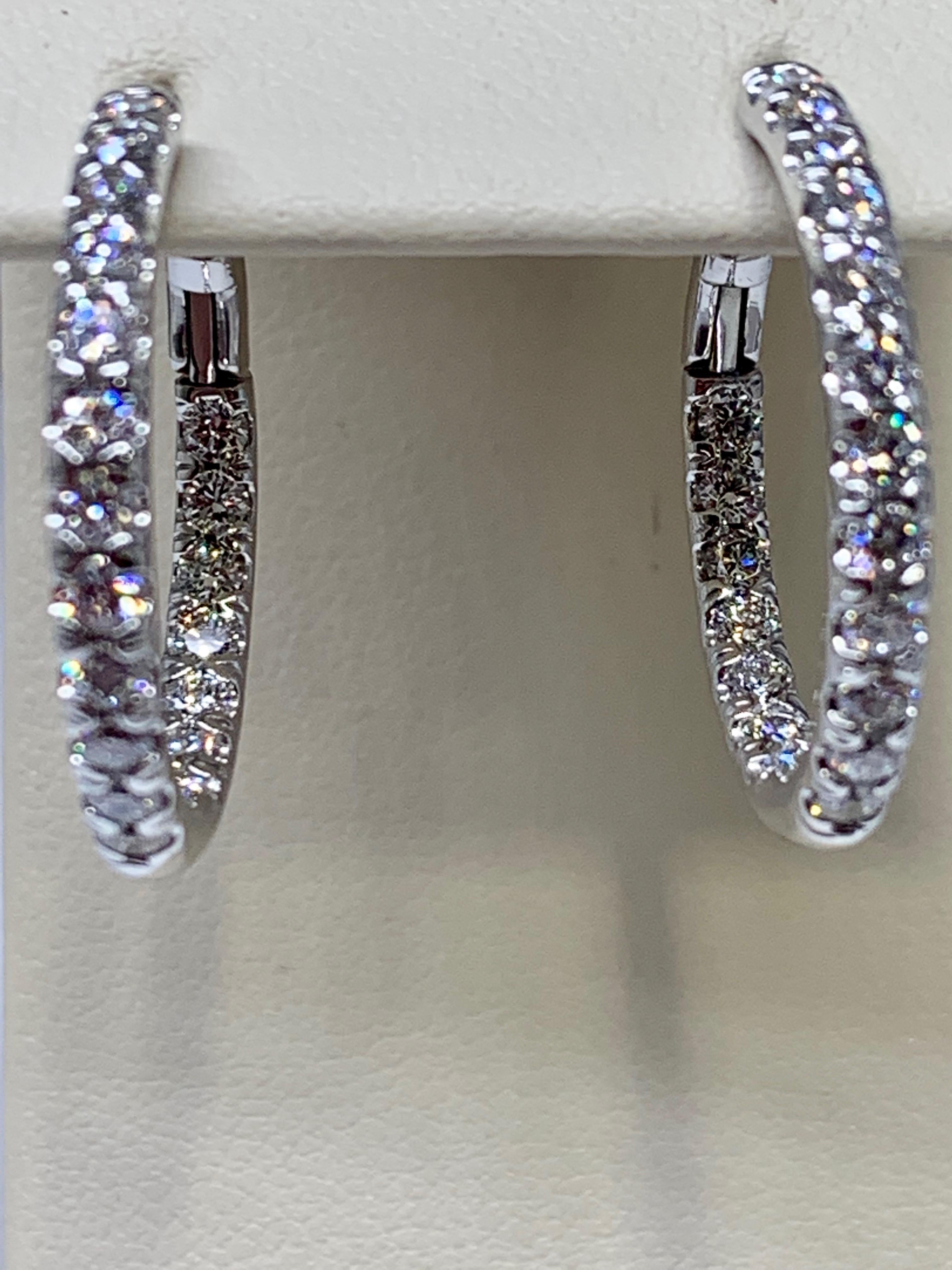 These classic round diamond hoops are made of 18K white gold and include a total diamond weight of 1.30 carats. These earrings feature and inside-outside diamond pave design and are 17mm in diameter. These hoops include sturdy lever-backs for