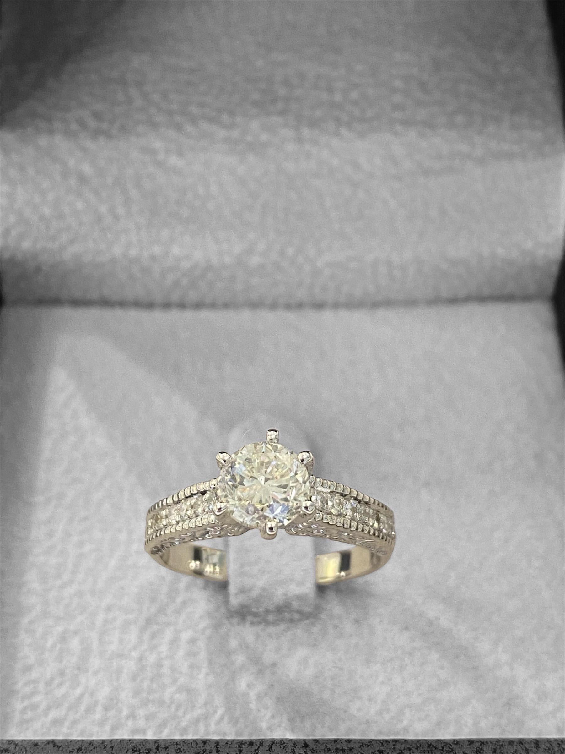 Il s'agit d'une magnifique bague en or blanc 14 carats, ornée d'un diamant central de 1 carat, entouré de (24 points) petits diamants. Le bracelet est également gravé de motifs de vigne, ce qui ajoute une touche élégante et détaillée au