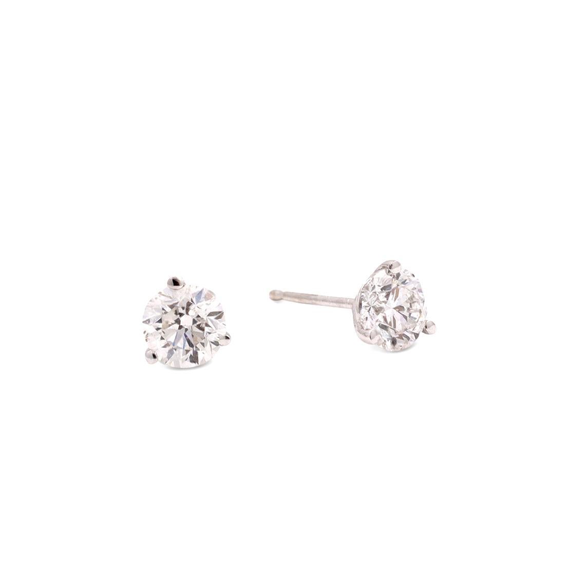 A stunning pair of diamond solitaire stud earrings crafted in 18 karat white gold. The earrings feature round brilliant cut diamonds estimated 0.96 carat total weight (H color, SI2 clarity). The earrings measure 5.2mm. Stamped 18K in the post and