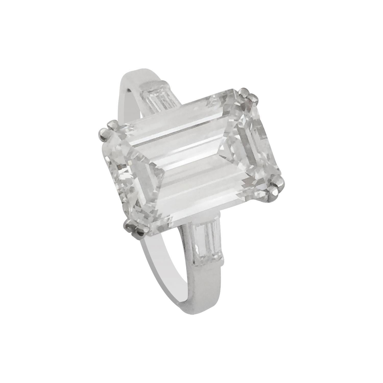 750/000 (18kt) White gold and platinum ring set with a 3.82 carat emerald-cut diamond.
The stone is laid in a 4 double prongs basket setting.
On the mounting, the center diamond is flanked by two diamond baguettes weighing about 0.50 carat.  
Weight