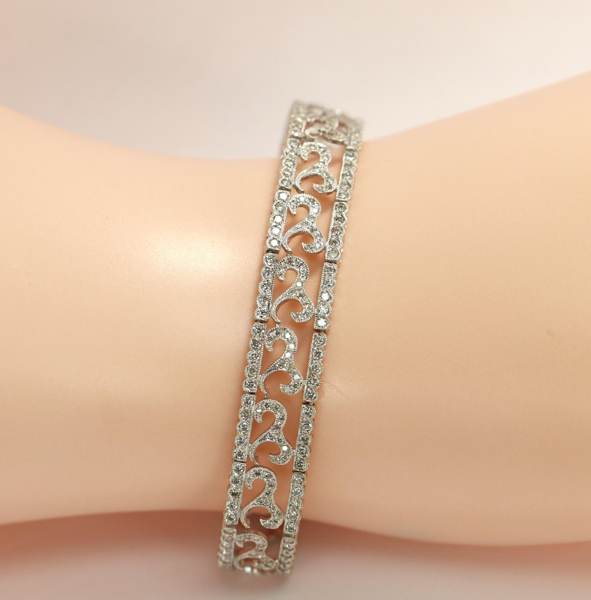 An antique style bracelet featuring a scrolling or wave design in 18k white gold, and measuring approximately 3/8 of an inch wide and 7 inches long. This classic bracelet is set with 2 1/2 carats of round brilliant cut diamonds.