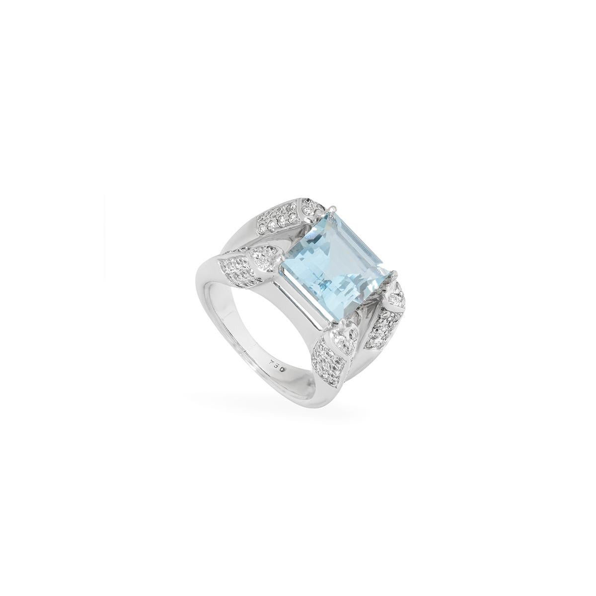 An 18k white gold aquamarine and diamond dress ring. The ring is set to the centre with a square step cut aquamarine, weighing approximately 3.91ct, displaying a deep even blue throughout. The stone is set within a diamond set mount of which