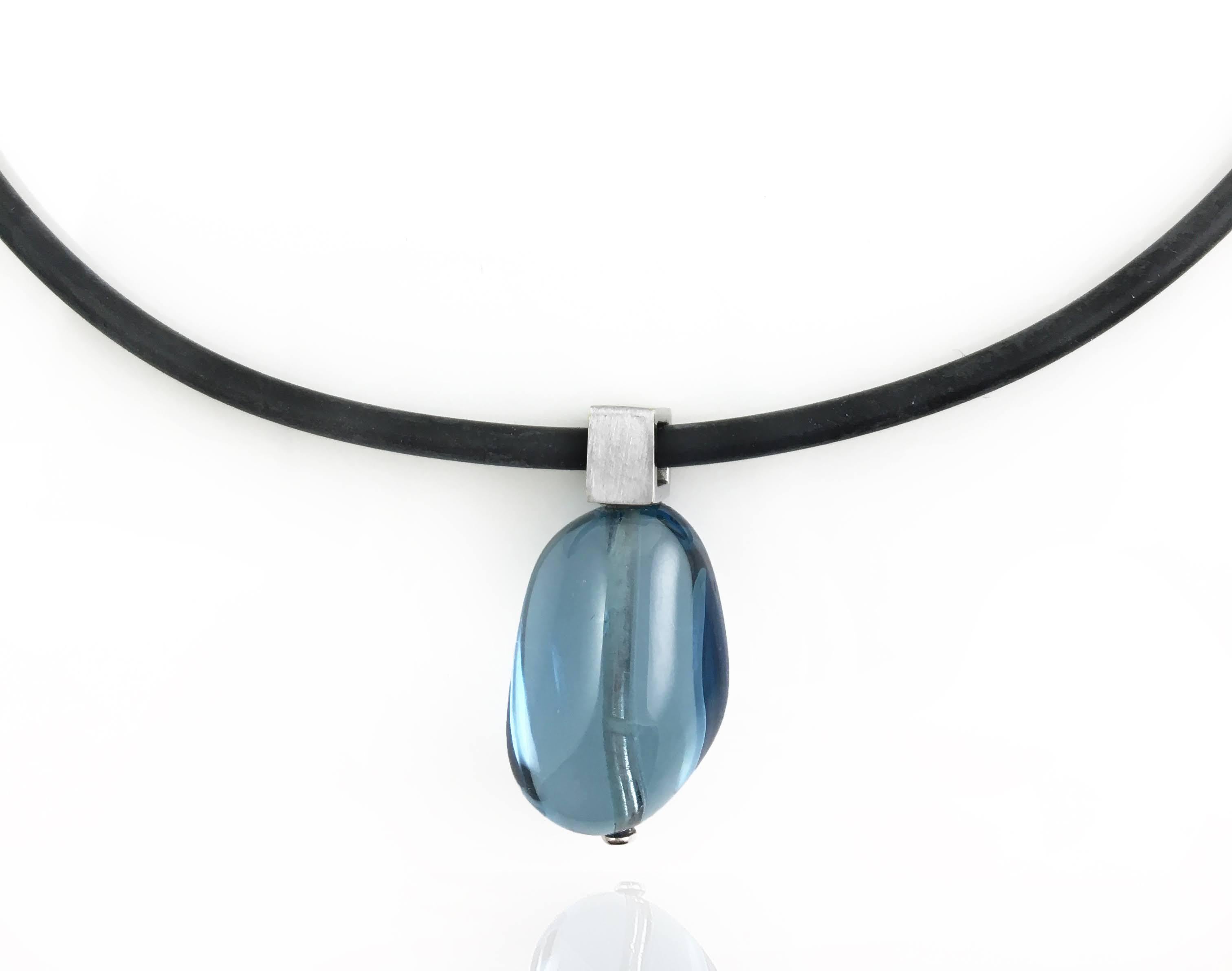 One of a kind. Stunning White Gold Bail with Blue Topaz Pendant on Rubber Cord. The smooth organic drop bead looks like water. The 14 karat white gold bail is 7mm square with a brushed finish. The pendant hangs from a 3mm black rubber cord with a