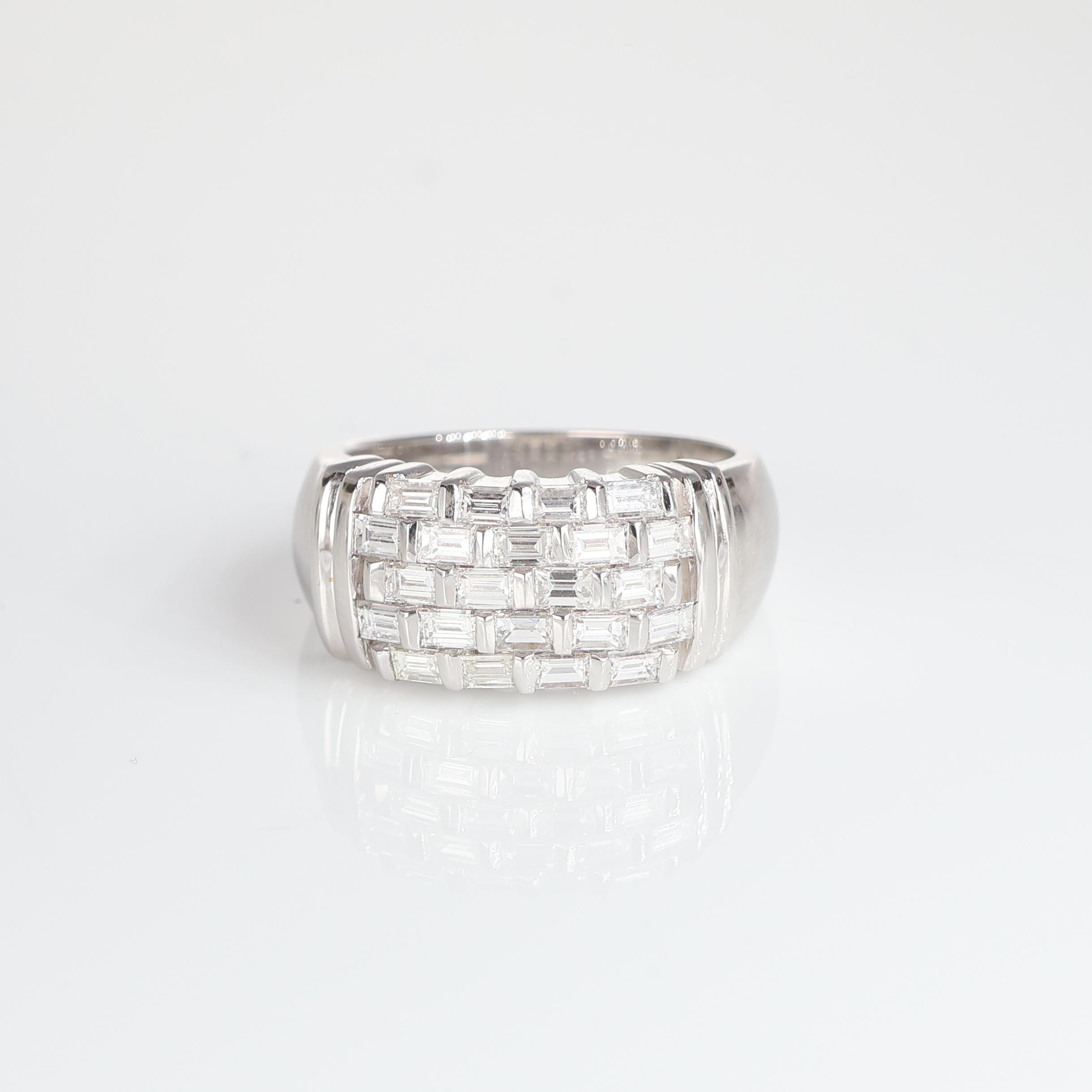 This elegant 18kt white gold band ring features a striking centerpiece adorned with baguette-cut natural white diamonds, meticulously set to create a modern geometric design. Totaling 1.40 carats, the diamonds, with their exceptional D E F color and