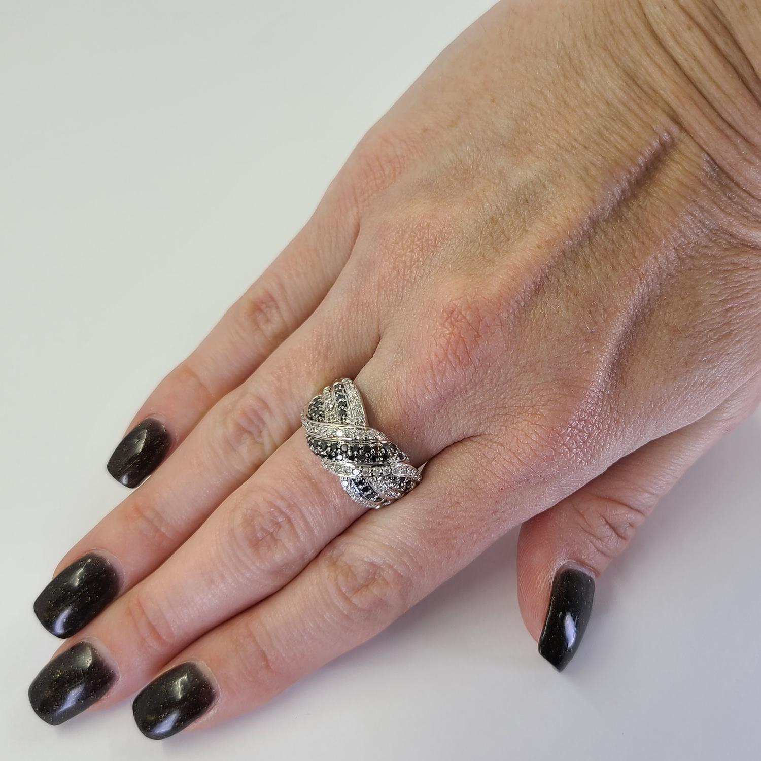 14 Karat White Gold Wide Ring Featuring Crossover X Design. 42 Black Diamonds Total Approximately 0.65 Carat, and 48 Round Diamonds Of I1 Clarity & H Color Total Approximately 0.50 Carats. Finger Size 7.25; Purchase Includes One Sizing Service.