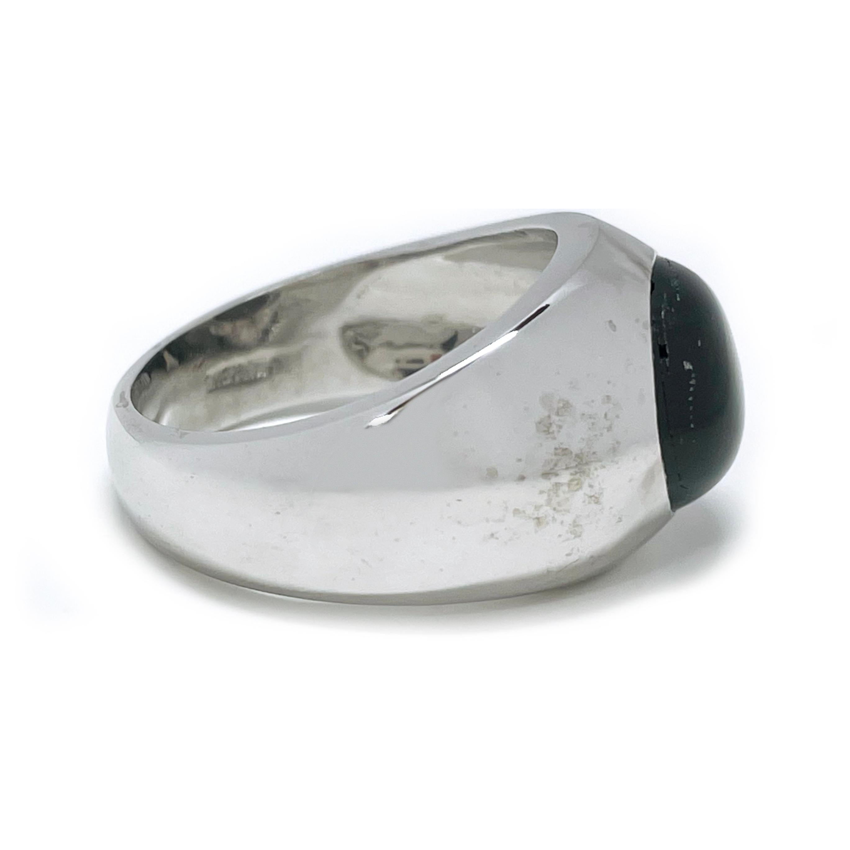 18 Karat White Gold Black Star Sapphire Ring. The ring features a bezel-set oval black star sapphire. The six-star sapphire has great presence with light. The sapphire measures 13.5 x 11.00mm and the ring size is 8 1/2. The ring has a smooth shiny