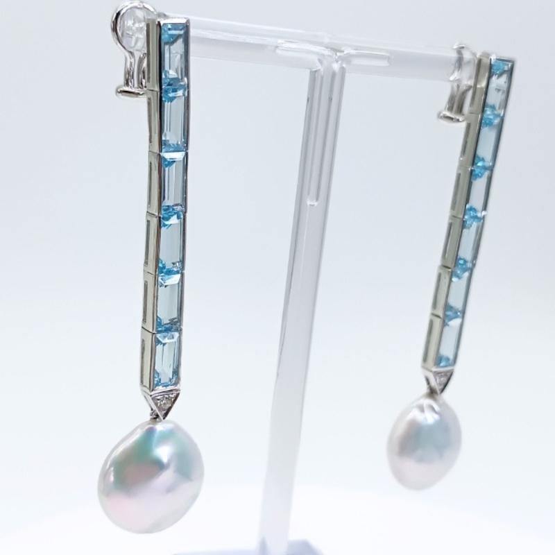 Long earrings in white gold with omega clasp.
12 baguette-cut blue topaz, 2 brilliant-cut diamonds and two coin pearls.

18k White Gold
12 Blue Topazes 20.36k
2 Diamonds 0.16k
2 Coin Pearls