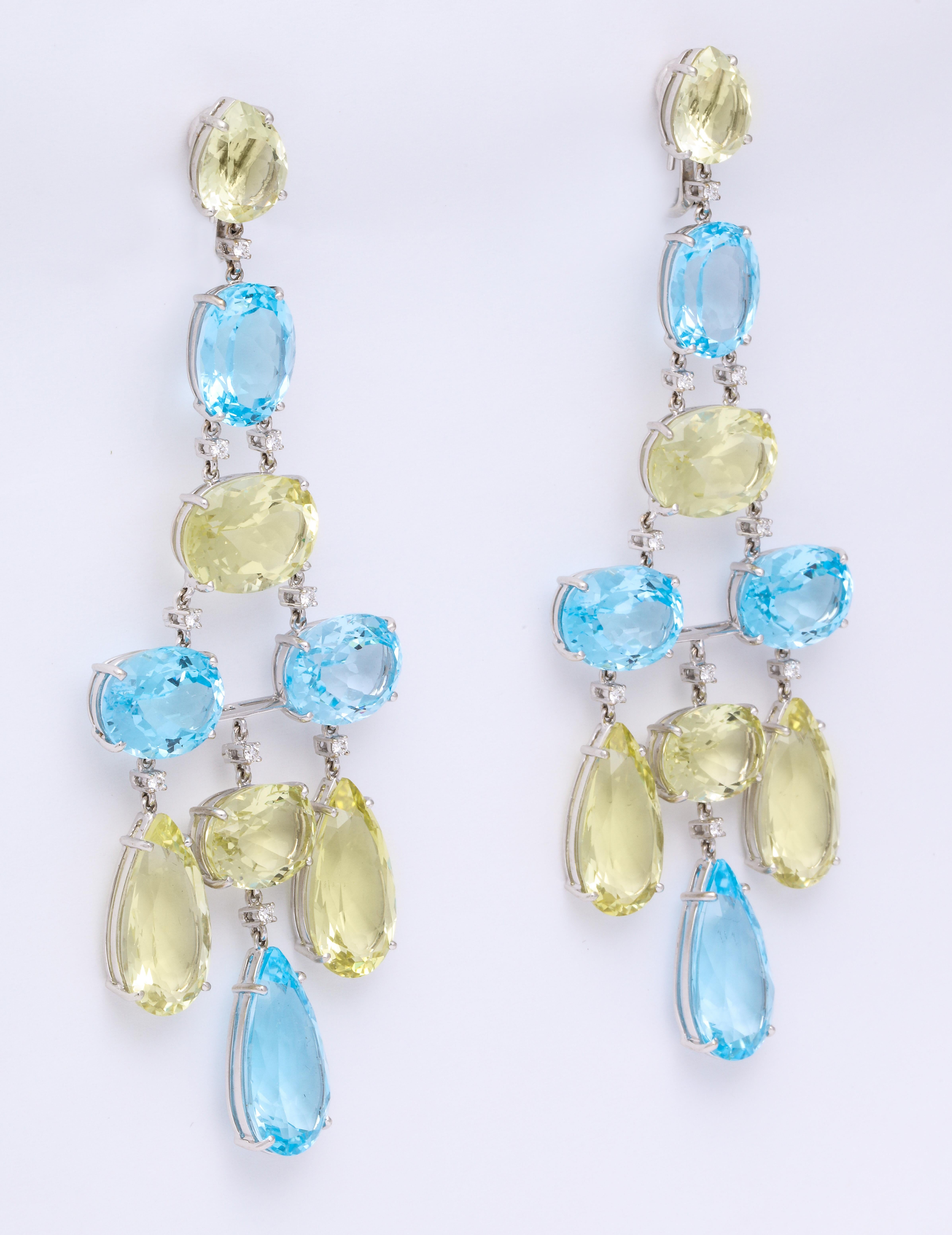 Flirty and Fun 18K white gold generously scaled trapeze earrings mounted with faceted pear-shaped and oval blue topaz alternating with pastel peridot, combined weight: 142.81 carats, set on delicate prongs, and articulating round brilliant-cut