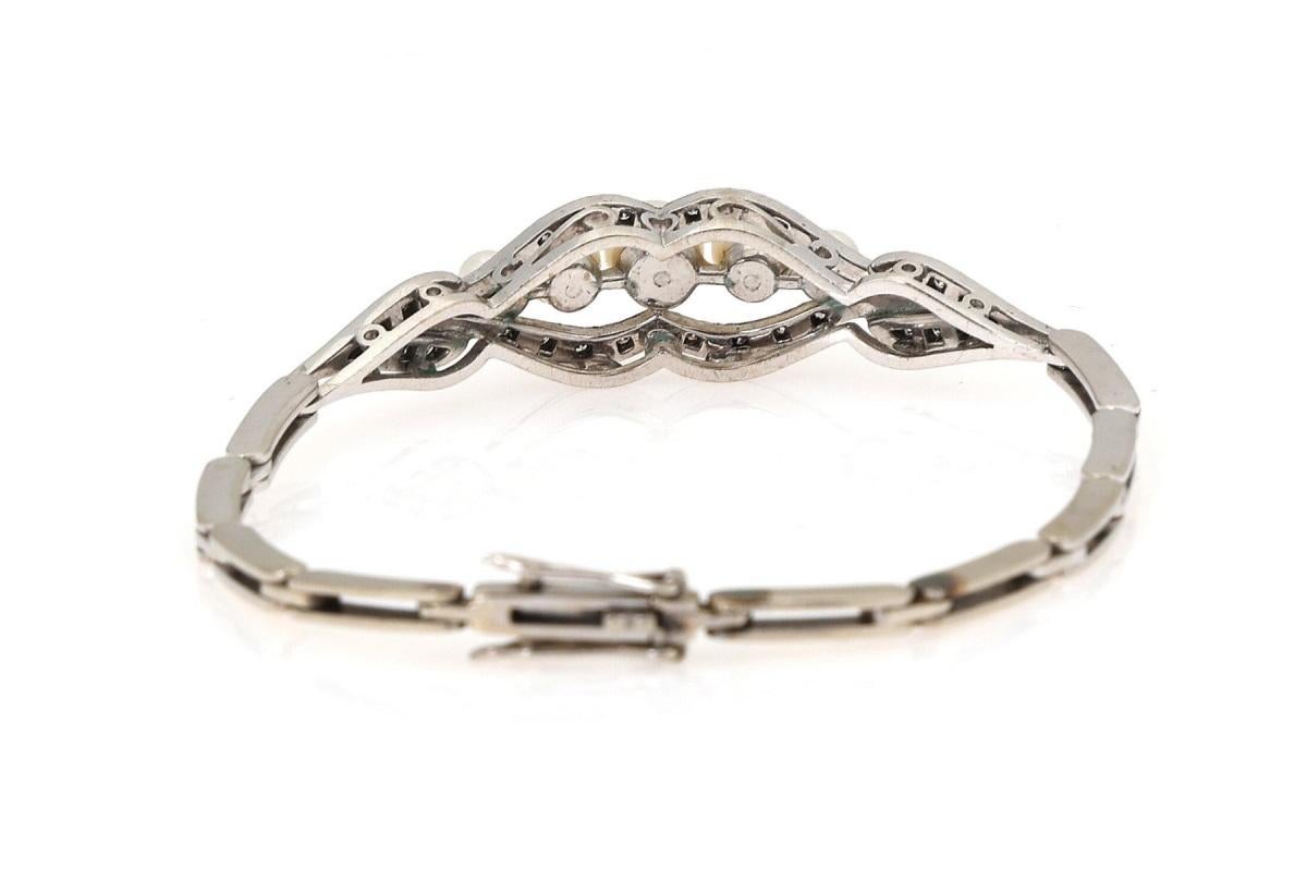 Pulsera de oro blanco de 14 quilates.

Bellamente decorada con cinco perlas cultivadas blancas rodeadas de 30 diamantes en talla 8/8 con un peso aproximado de 0,18 ct.

La pulsera se cierra con un broche con un ocho de seguridad adicional.

Origen: