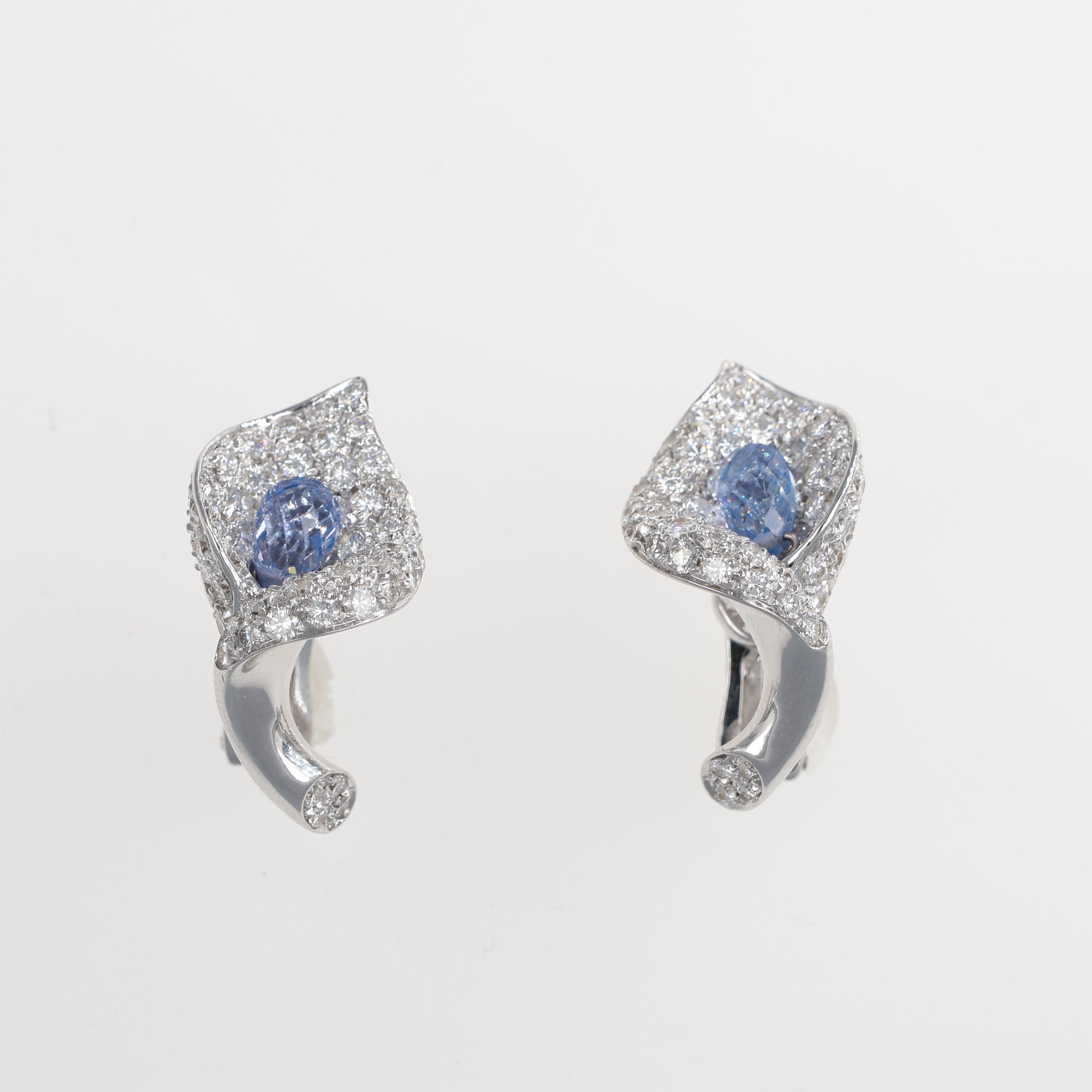 A refined pair of earrings crafted in 18K white gold, designed in the shape of elegant calla lilies. The surface is adorned with a pavé of brilliant-cut diamonds, creating a dazzling effect that enhances the delicate curves of the design. At the