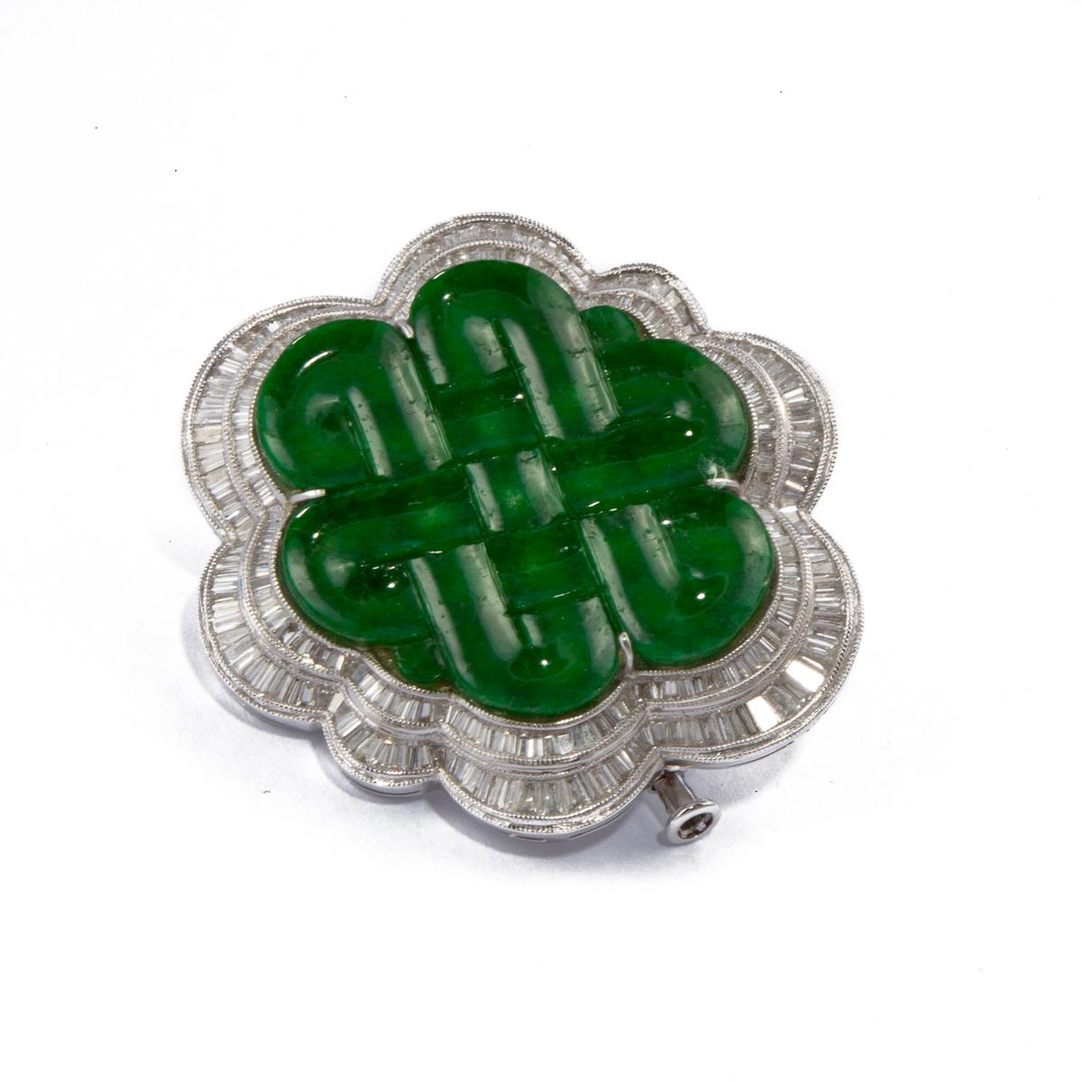 18K white gold pin/pendant featuring carved jade framed by a double row of tapered baguette diamonds.  The jade is carved in a crosshatch pattern.  There are 290 diamonds that total 6 carats.  Measures 1 3/8 inches across.  Closure is a trombone