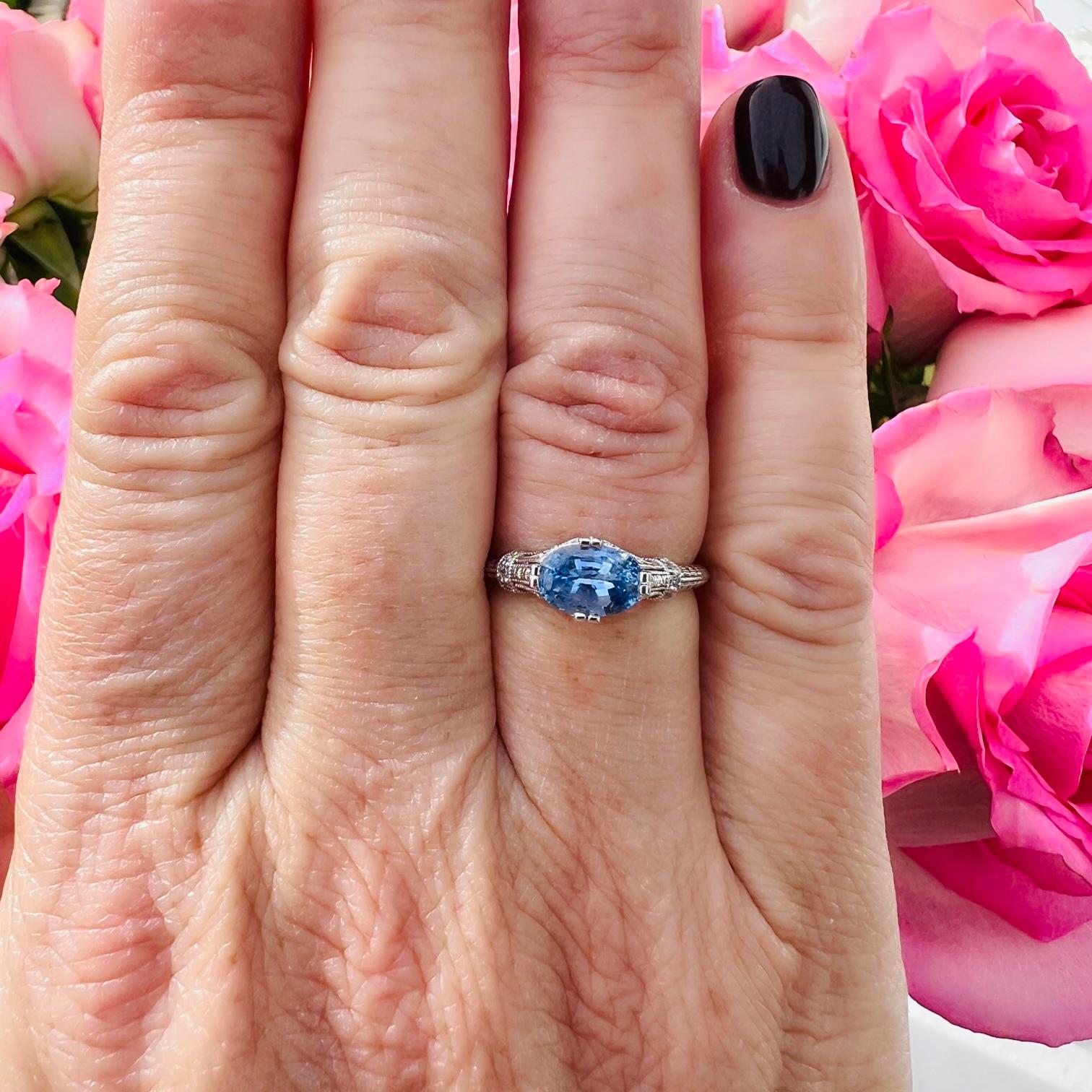A unique ring that is sure to become a favorite! This 14 karat white gold beauty features an Oval Cut Ceylon Sapphire  horizontally set in a beautiful antique inspired ring. The vibrant blue sapphire weighs 1.43 carats and delivers excellent light