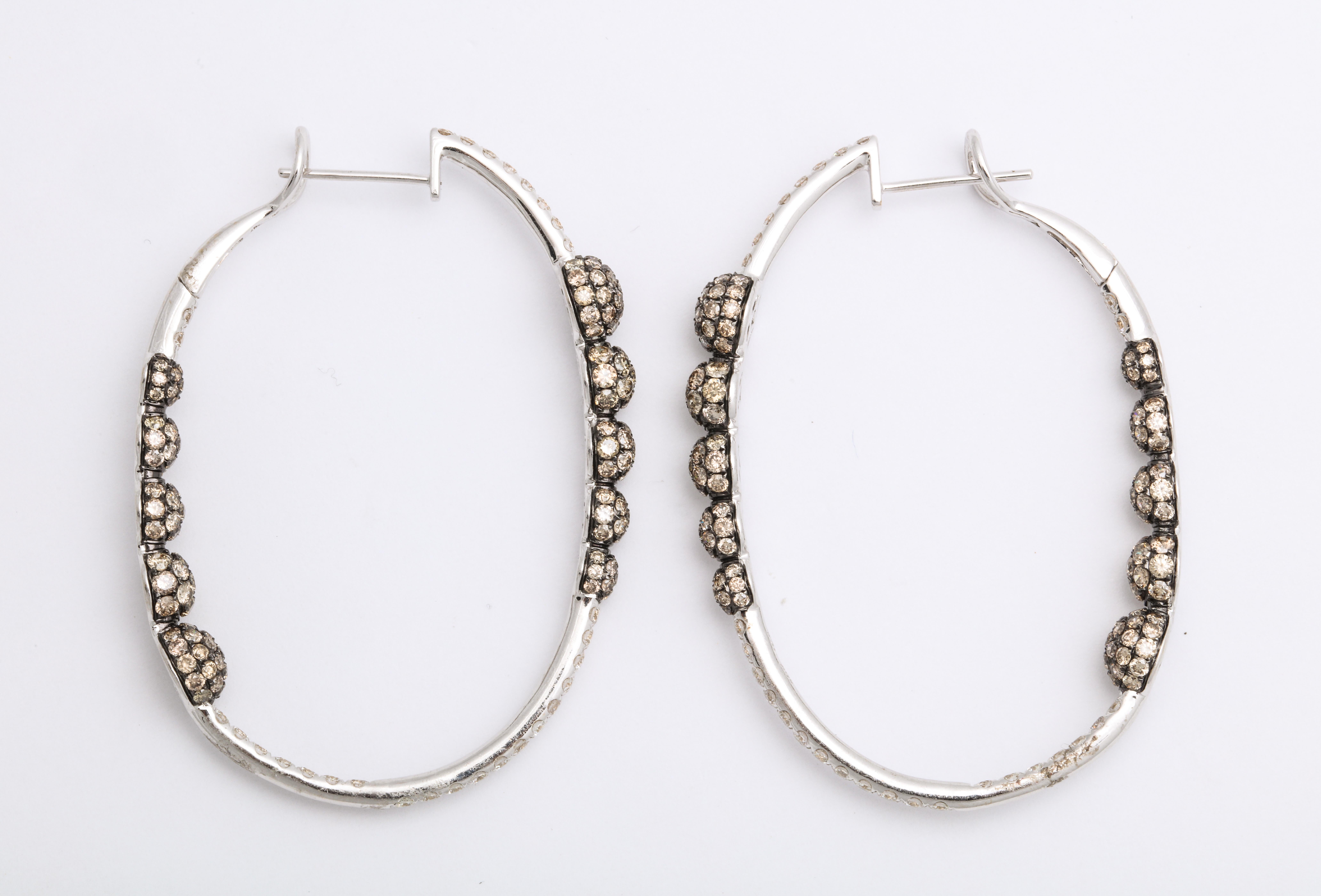 Oval 18K whole gold hoop earrings decorated with pave'-set round brilliant-cut colorless diamonds: 1.22 carats, mounted with gently graduating beads, decorated with natural cognac-color round brilliant-cut diamonds: 4.17 carats, with a black rhodium