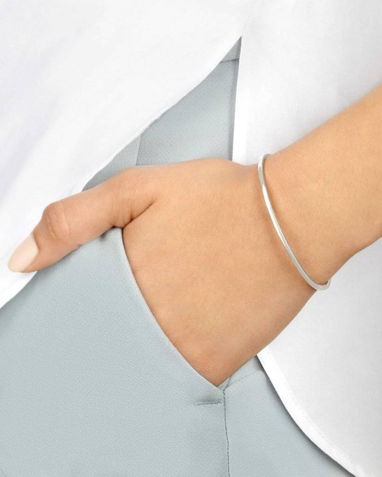 An elevated take on a jewellery basic, our slim cuff in 9-carat white gold has slightly pointed beveled edges and two sparkling white diamonds. Total diamond carat weight .016 carats. The bracelet is slightly flexible to enable a customised fit for