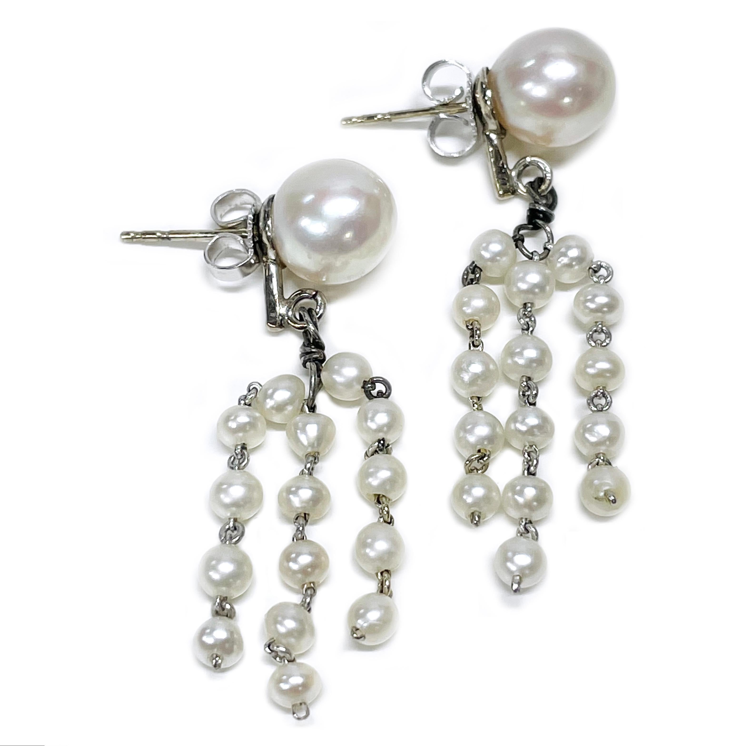 14 Karat White Gold Cultured Pearl Dangle Earrings. One pair of cultured pearl earrings. Each earring is comprised of one 8.0 to 8.5mm diameter close to spherical cultured pearl peg set onto a pad with three strands of five pearls each dangling from