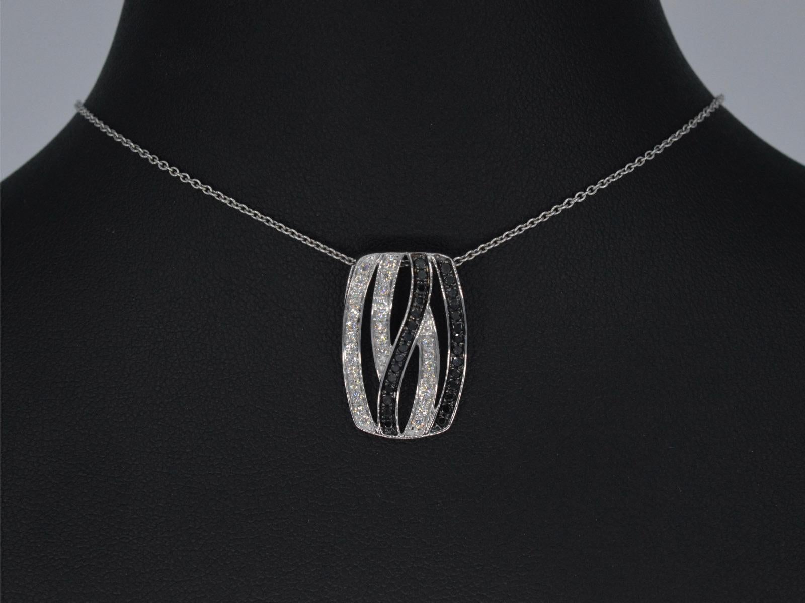 This 18K white gold pendant is a high-quality piece of jewelry, crafted from a premium metal that is renowned for its lustrous and durable properties. The pendant features a unique design, incorporating both white and black brilliant diamonds of