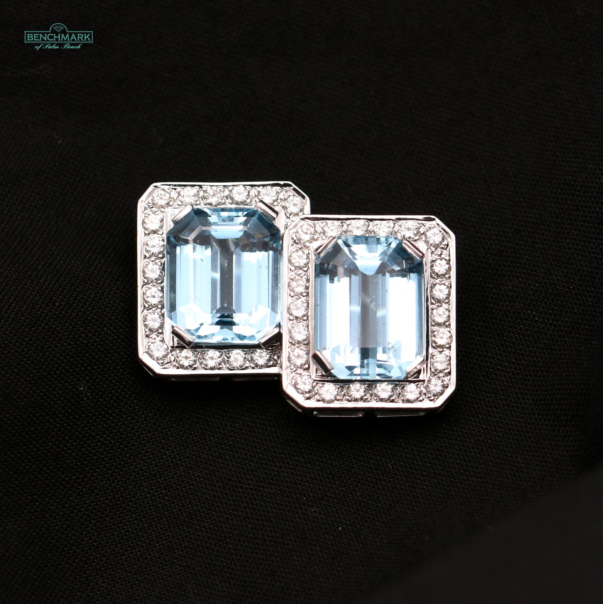 A pair of 14K white gold earrings, each centered around an emerald cut aquamarine, surrounded by 22 diamonds. Each earring measures 7/8 of an inch long and 3/4 of an inch wide, and is crafted in 14K white gold. They are a classic style, and are the