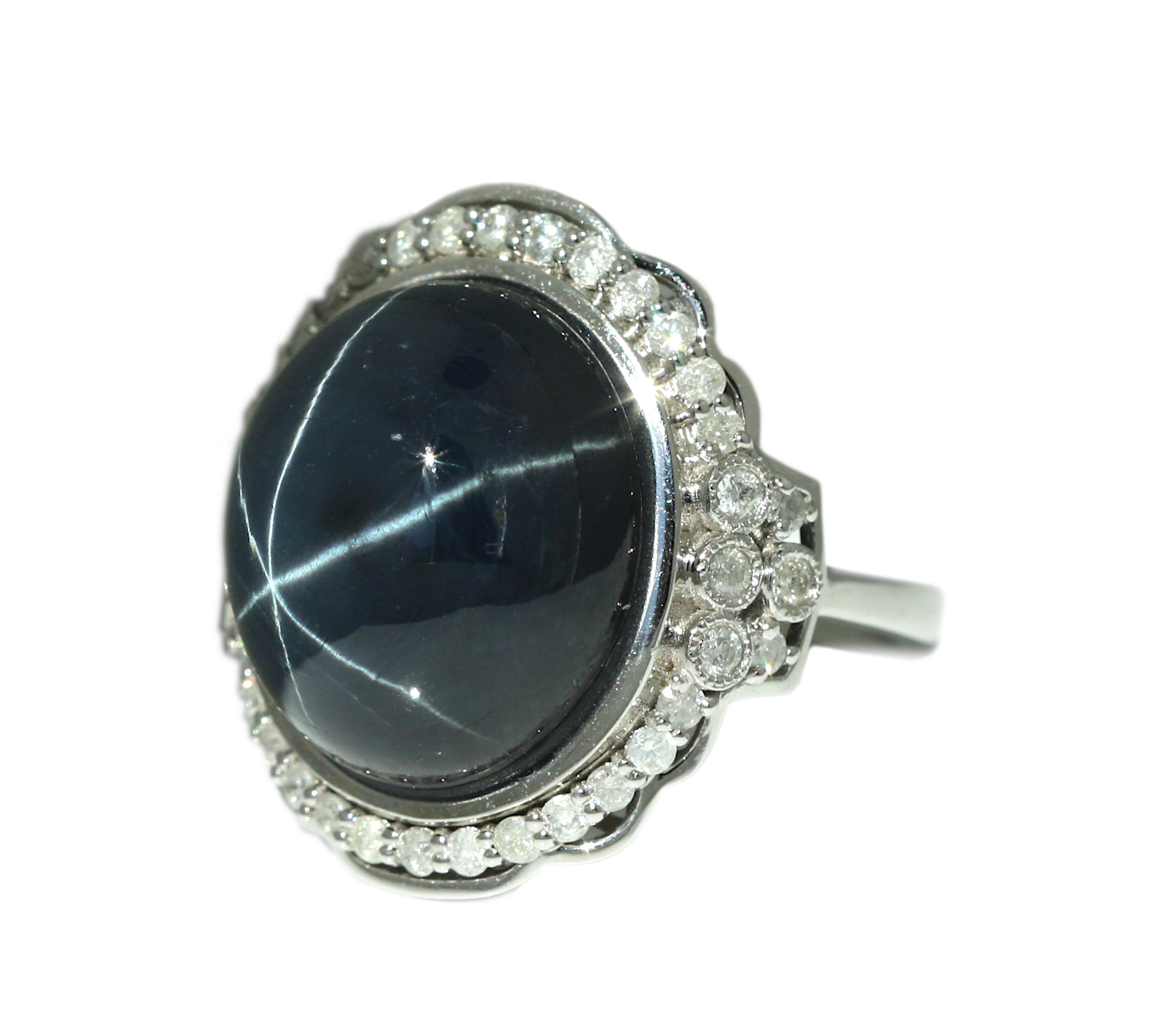 White Gold Diamond and Blue Sapphire Ring 
Weighing 23.95 cts. 
Centering one oval shape, cabochon cut dark blue sapphire 
Accented by an oval surround of round, brilliant cut diamonds, 14KT
Total Weight 10.80 grams