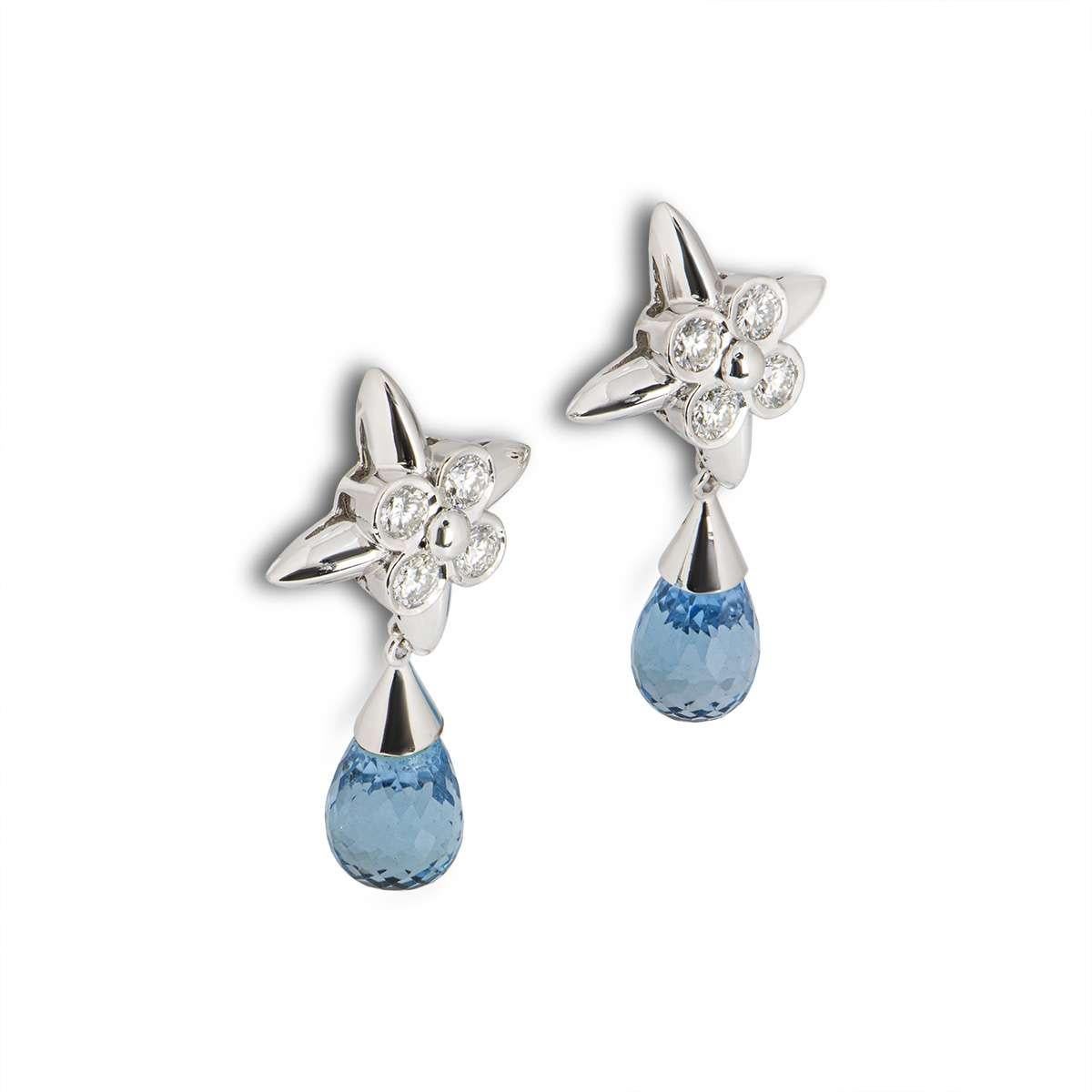 A pair of 18k white gold drop earrings. The earrings feature a flower motif set with diamonds, complemented by a briolette cut blue topaz. There are 8 diamonds in total with a weight of 0.72ct and 2 topaz totalling 9.83ct. The earrings measure 3.1cm