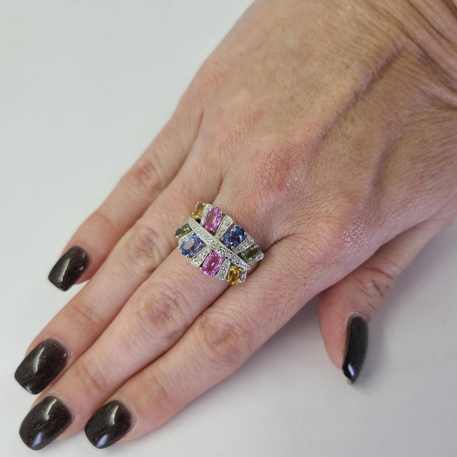 14 Karat White Gold Ring Featuring 8 Oval Cut Multicolor Sapphires Totaling Approximately 5 Carats Accented By 29 Round Diamonds of SI Clarity & G/H Color Totaling 0.15 Carats. Finger Size 7; Purchase Includes One Sizing Service. Finished Weight Is
