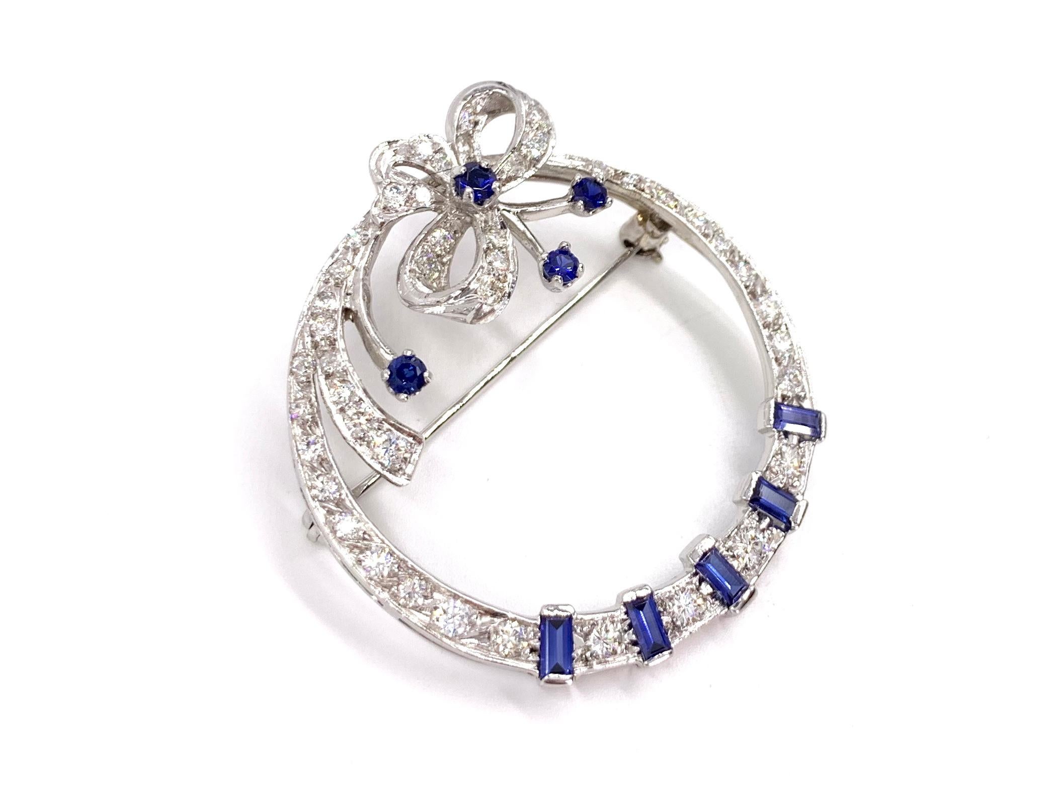 An exquisite 14 karat white gold bow garland style circle brooch featuring high quality blue sapphires and diamonds. Brooch has an approximate diamond total weight of 2 carats at approximately G color, SI1 clarity. Nine vivid, very well saturated