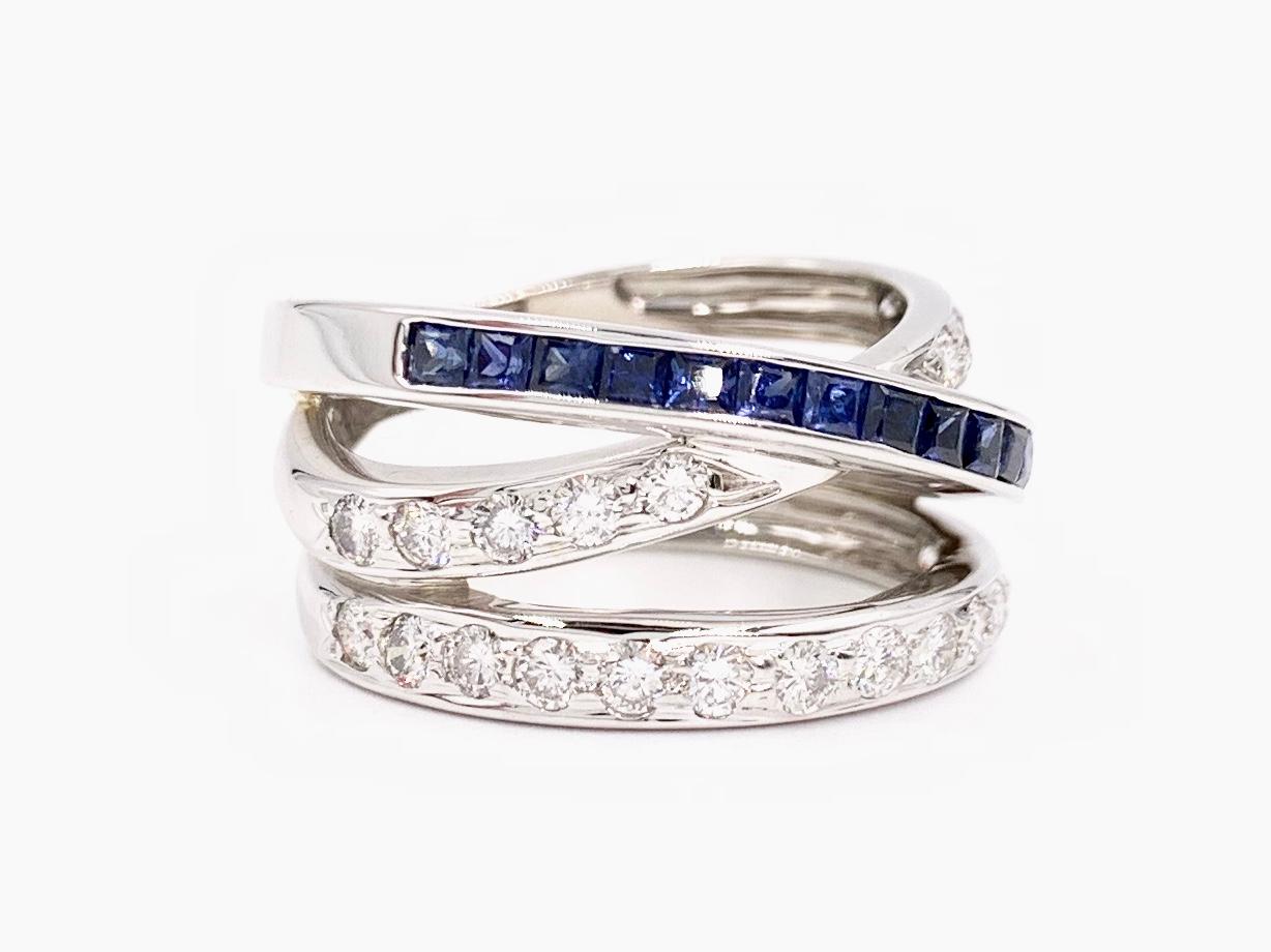 A fashionable and fun 14 karat white gold three row crossover ring featuring princess cut blue sapphires and round brilliant white diamonds. 24 prong set diamonds have an approximate total weight of 1.20 carats with a grading of approximately G