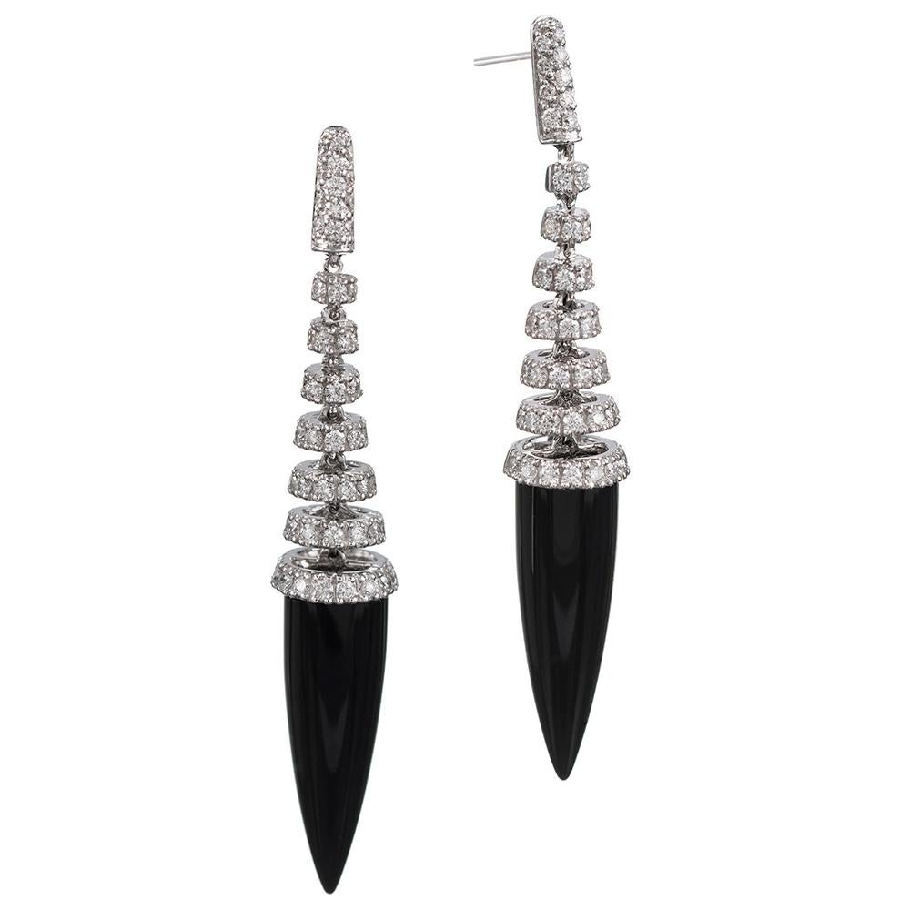 These heavily mobile modern ear sculptures of 18 karat white gold, brilliant white diamonds and smooth, tipped punctuations of black onyx offer a unique adornment for the enthusiast of modern design. The sleek, tapered shape of the stone makes for a