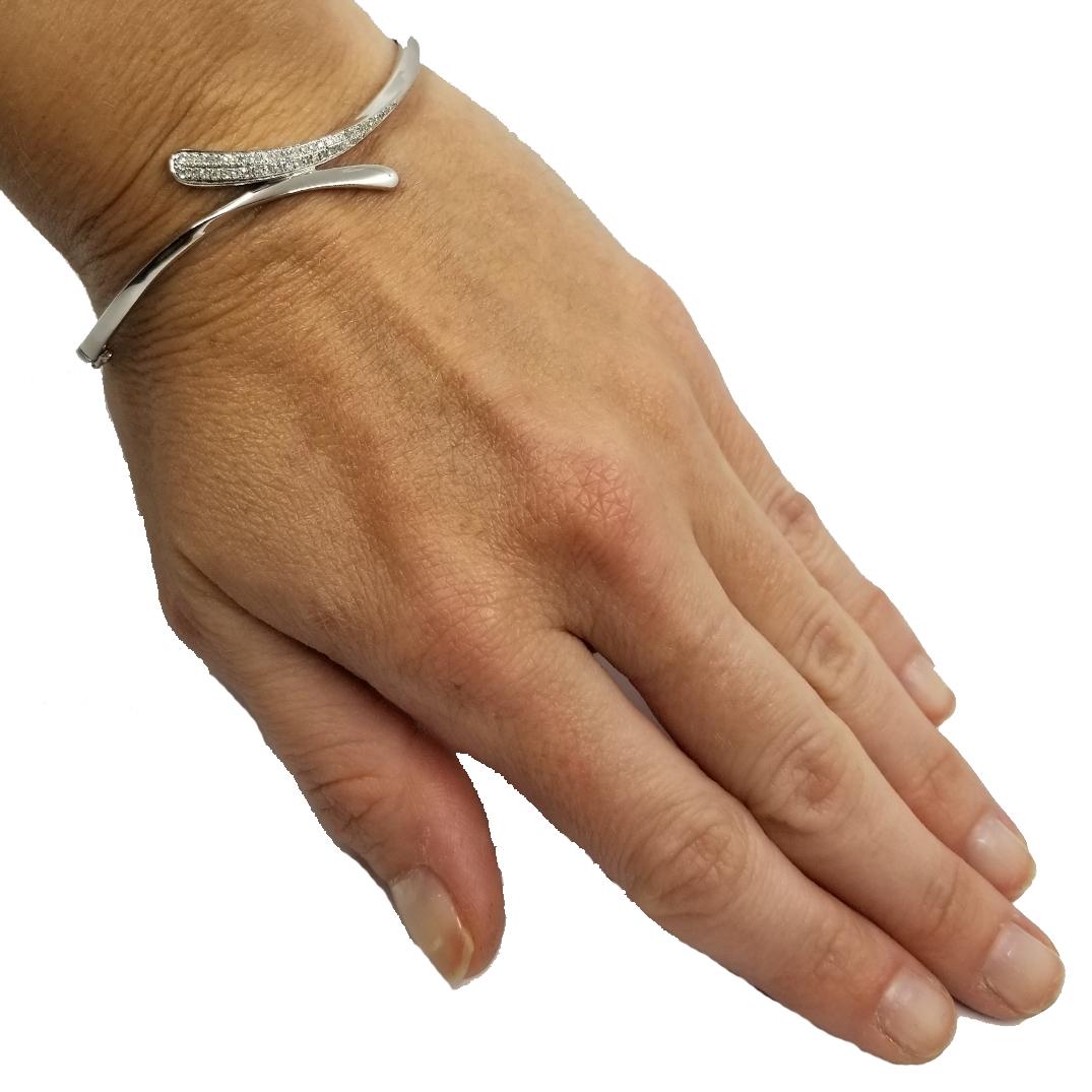 14 karat white gold bypass bangle featuring 0.25 carat total weight of pave round diamonds on one side. Hinged Design. Professionally cleaned and polished to remove scratches. Total Weight is 8.7 grams.