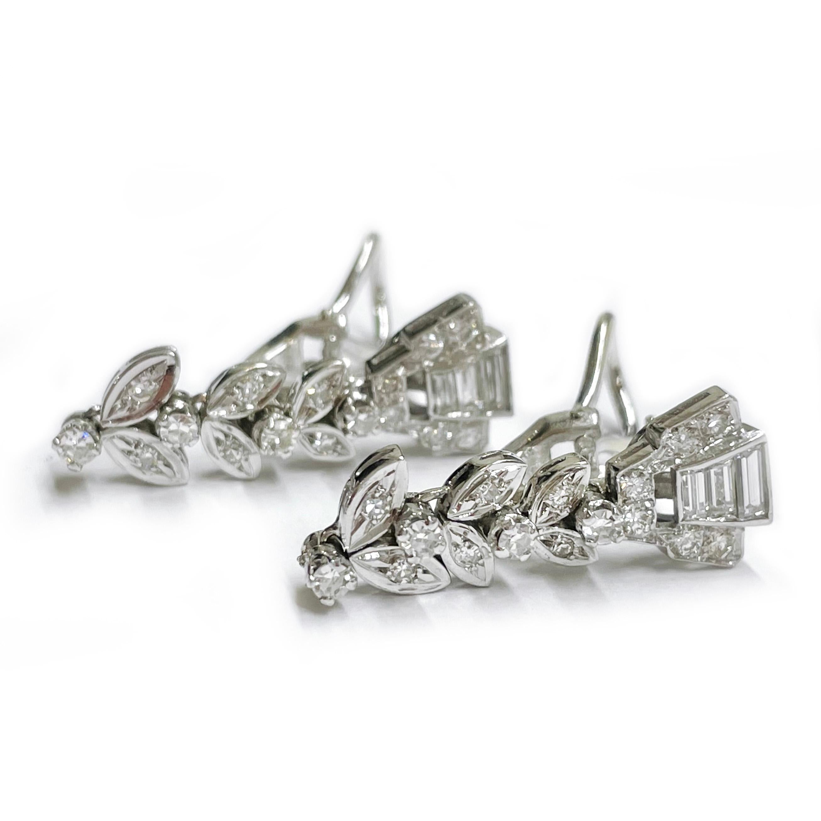 18 Karat White Gold Diamond Dangle Earrings. Each earring features three straight baguette-cut diamonds, twelve bead-set, and four prong-set round diamonds. In total there is two 3.5mm x 1.5mm, two 3.1mm x 1.5mm, and two 2.5mm x 1.5mm baguette