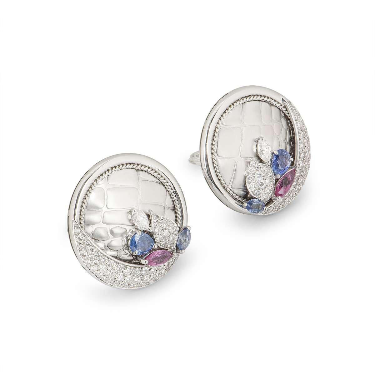 A pair of 18k white gold diamond, sapphire and ruby earrings. The earrings are set with round brilliant cut diamonds and a marquise cut diamond totalling approximately 3.04ct. Complementing the diamonds is a single ruby totalling approximately