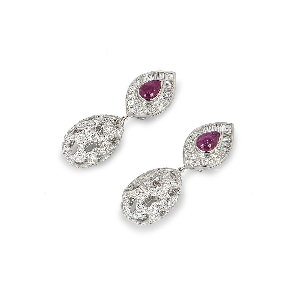 An exquisite pair of 18k white gold diamond and ruby drop earrings. The top part of the earrings features cabochon pear shaped rubies in a rub over setting set to the centre with an approximate combined weight of 4.00ct, surrounded by an asscher cut