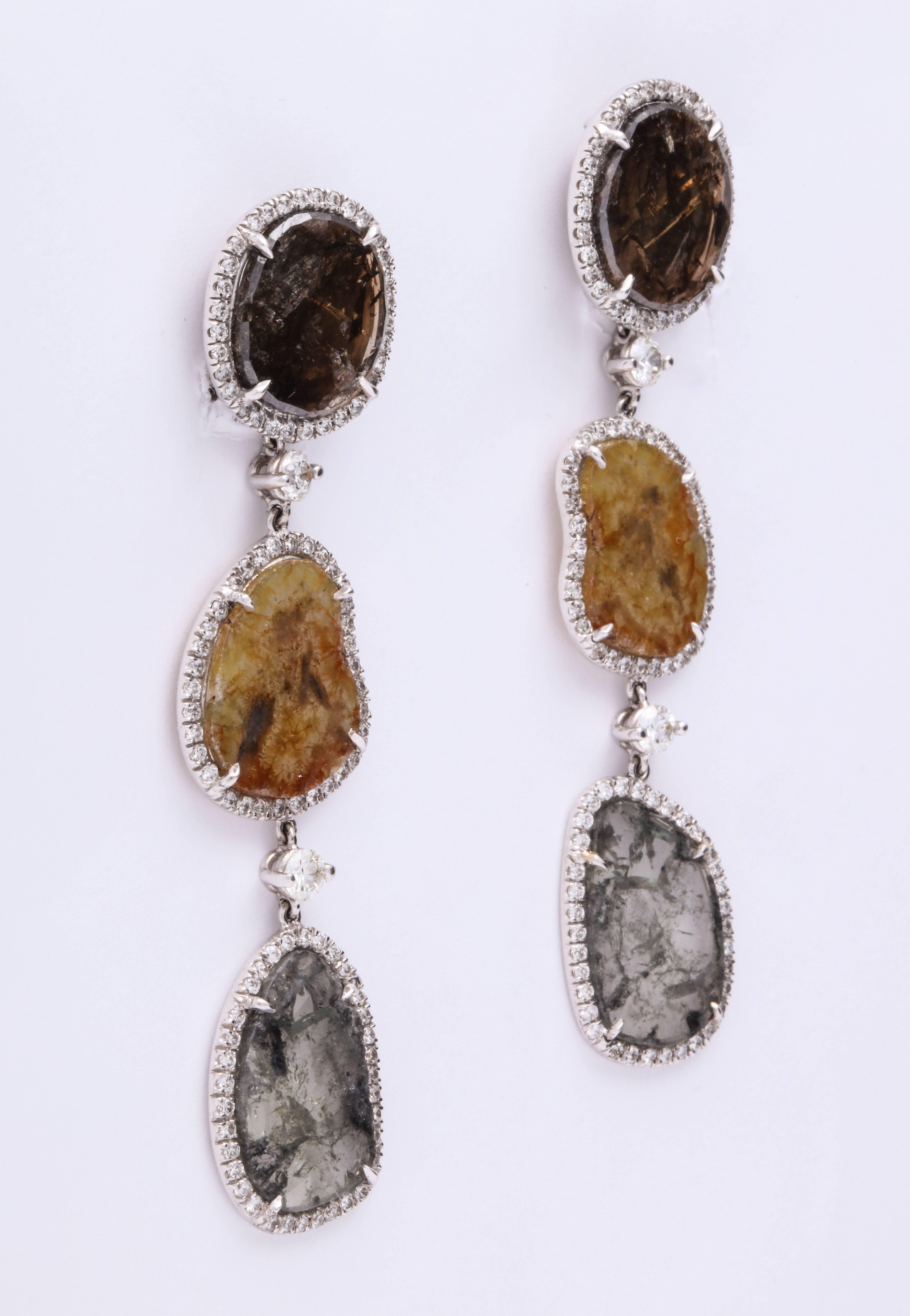 Contemporary and current 18K white gold earrings mounted with 6 free-form  translucent natural color diamond slices, colors from top to bottom: coppery, jasper, and silvery, combined weight: 12.07 carats, separated with round brilliant cut round