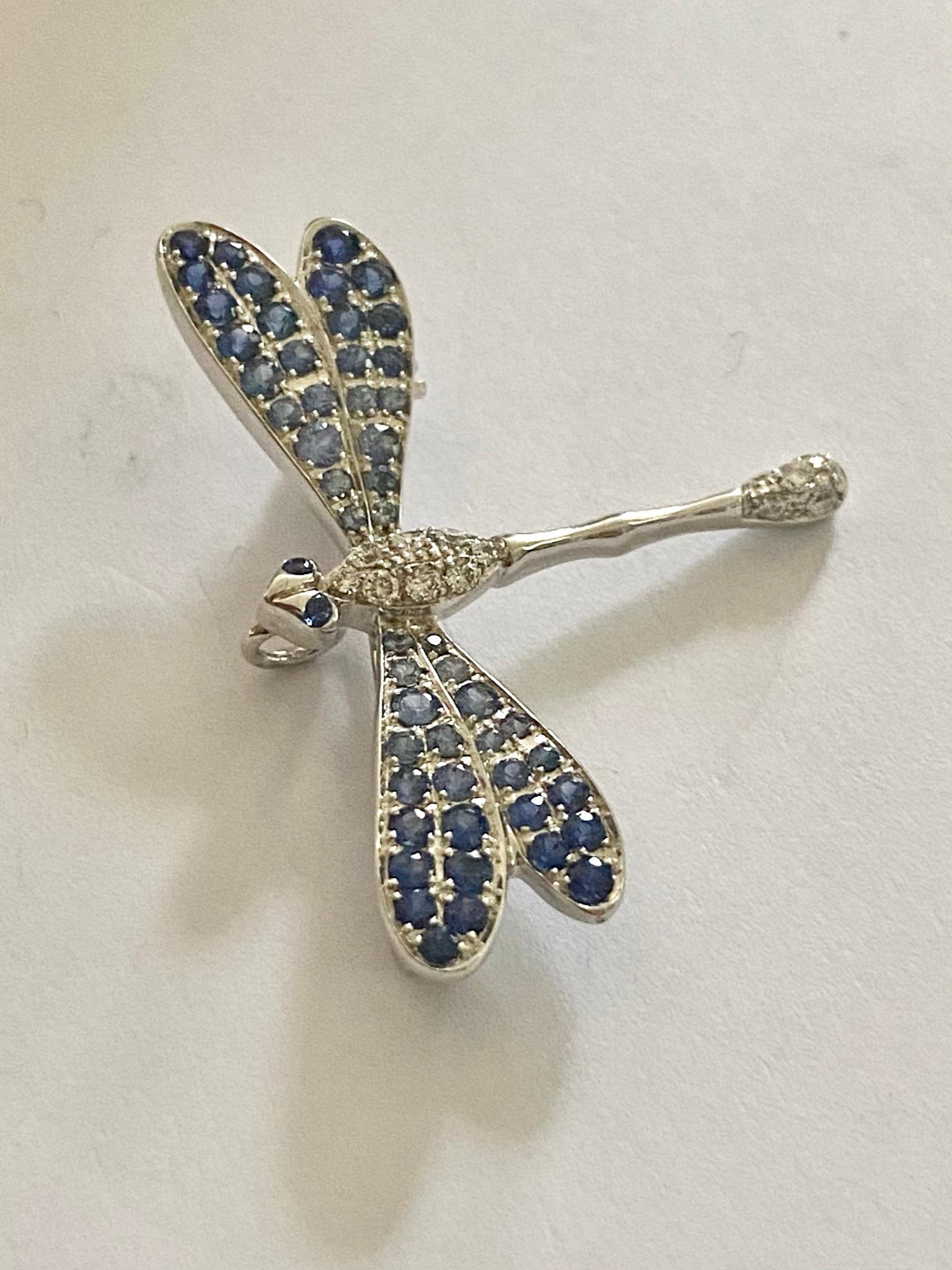 An 18 karat white gold brooch in the shape of a dragonfly.
(Can also be worn as a pendant)
14 brilliant cut diamonds = 0.12 ct VS-F-G
54 round mixed cut sapphires = 0.90 ct. (Treated)
size: 30 x 23 x 2 mm
Weight: 3.74 grams
Provided with the maker's