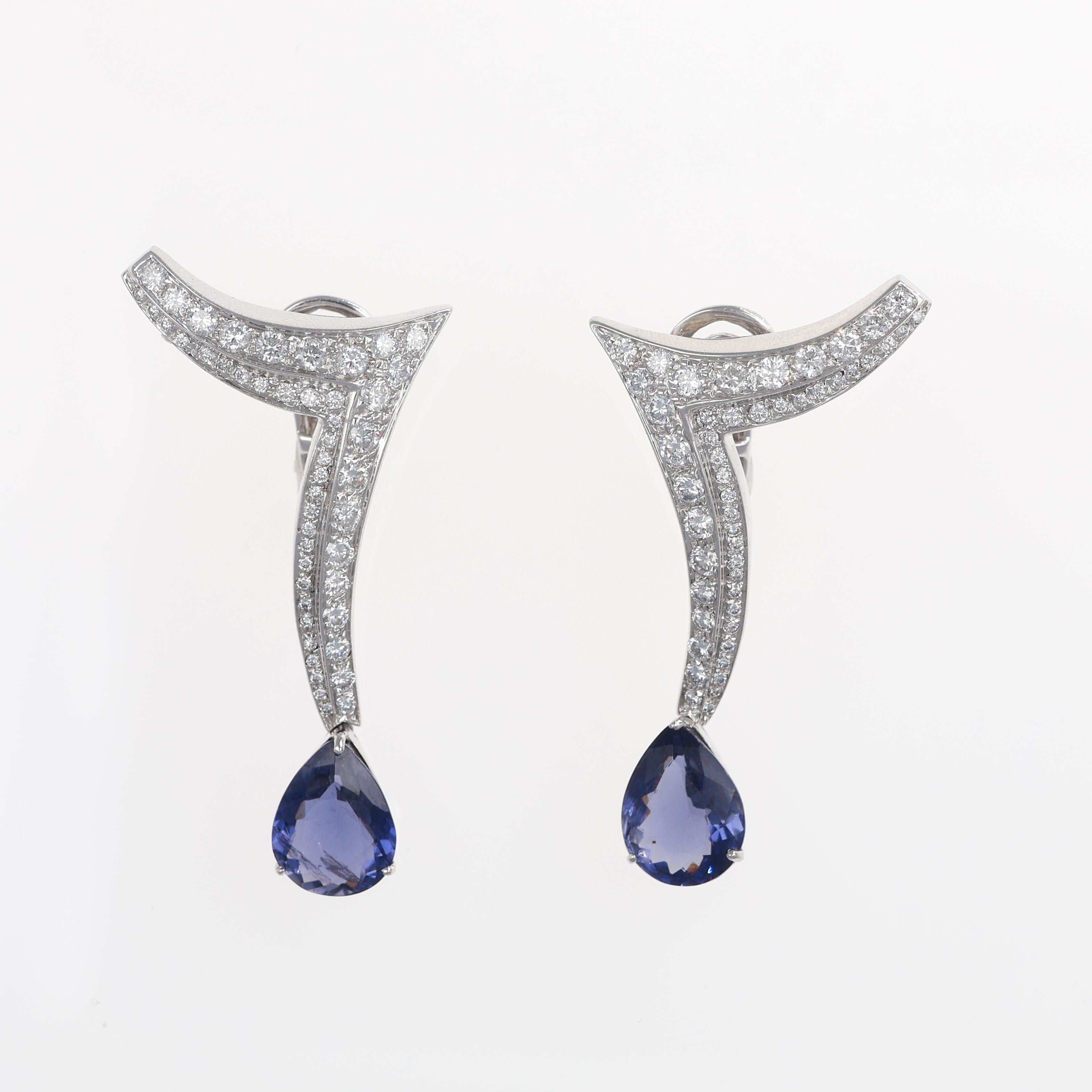 An elegant pair of drop earrings crafted in 18K white gold, featuring a sleek, contemporary design enhanced by a dazzling pavé of brilliant-cut diamonds. The earrings culminate in a striking pear-shaped iolite, totaling 5.20 carats, adding depth and