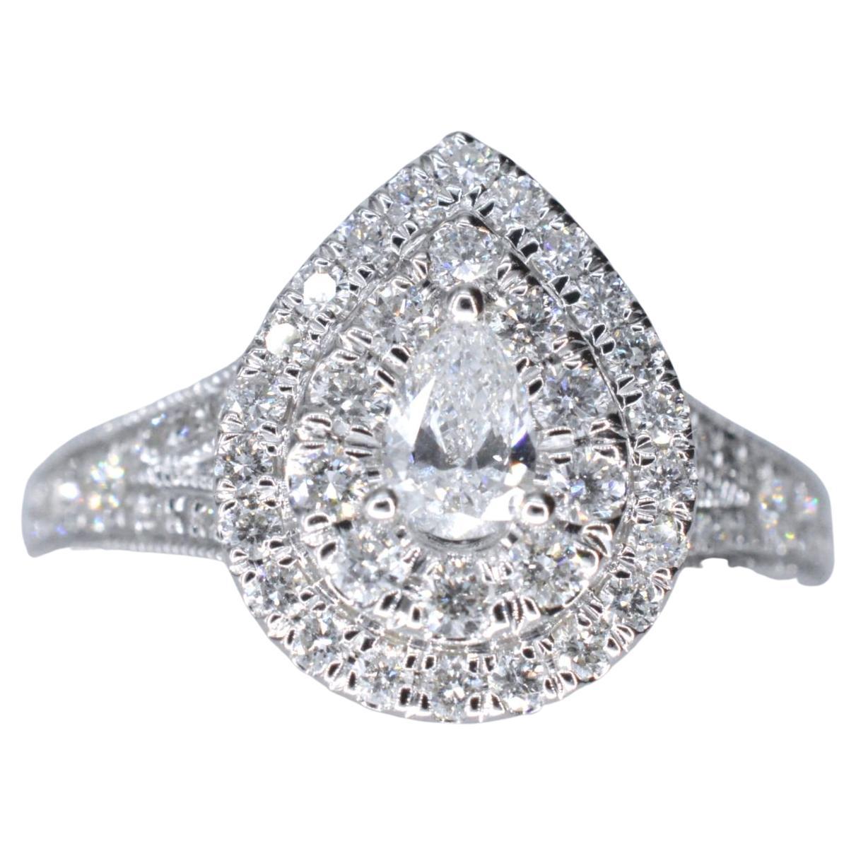 This beautiful white gold drop-shaped entourage ring is a stunning piece of jewelry that exudes elegance and sophistication. The ring features a pear-shaped center diamond that is held securely in place, showcasing its unique and exquisite shape.