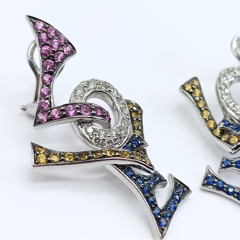 White Gold Earrings with the word LOVE and omega clasp.
36 brilliant cut diamonds, 30 blue sapphires, 35 yellow sapphires and 36 pink sapphires.

18k White Gold
36 Diamonds 0.58k
30 Blue Sapphires 0.53k
36 Yellow Sapphires 0.76k
36 Pink Sapphires