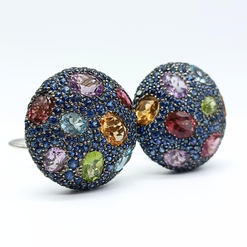 Weißgold-Ohrringe mit Omega-Verschluss.
Runde Form mit 367 blauen Saphiren, verschiedene Steine gefasst 3 Citrine, 3 blaue Topase, 4 rosafarbene Amethyste, 2 Peridote und 4 rosa Turmaline

Weißgold 18k
367 Blaue Saphire 9,20k
3 Zitrinen 2,74k
3