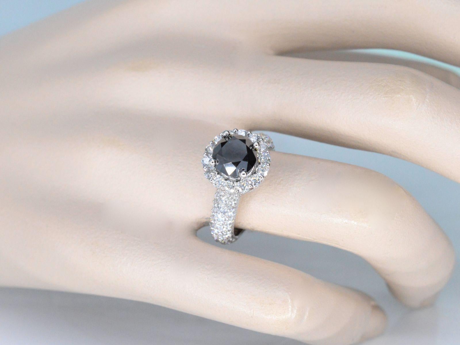 This exquisite white gold entourage ring boasts a stunning combination of large diamonds and a bold black diamond as its centerpiece. The black diamond, with a weight of 2.50 carats and brilliant cut, is enhanced for maximum brilliance, while the