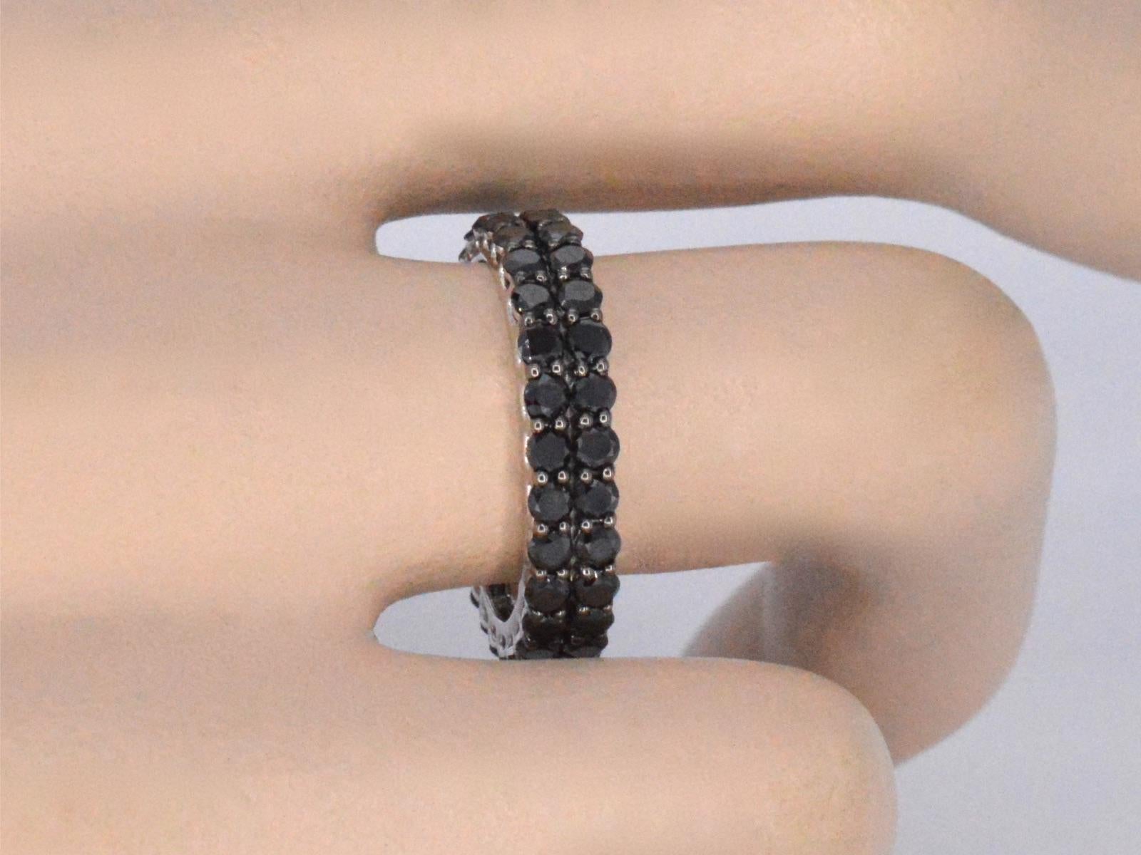 This white gold eternity ring is a sleek and stylish piece of jewelry, featuring a band of black diamonds that wrap all the way around the ring. The gold is a high-quality metal that is known for its durability and lustrous properties. The black