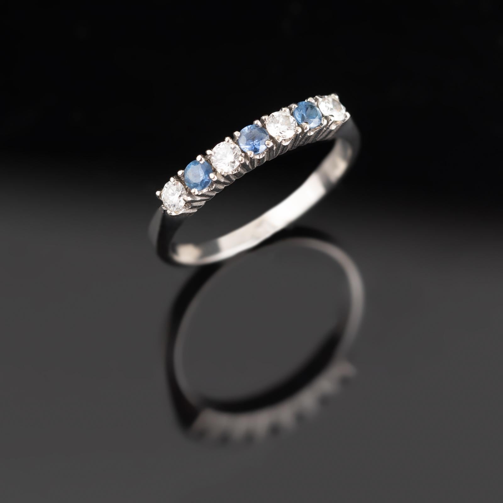 An elegant and timeless eternity band crafted in 18-karat white gold (750/1000), featuring an alternating sequence of deep blue sapphires and brilliant-cut diamonds. This refined design offers a harmonious contrast between the vibrant hue of natural