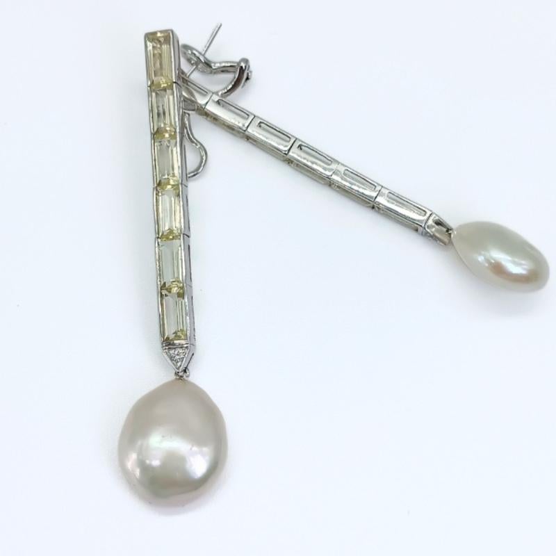 Orecchini lunghi in oro bianco con chiusura a omega.
12 quarzi limone taglio baguette, 2 diamanti taglio brillante e due perle a moneta.

Oro bianco 18k
12 Quarzo limone 16,30k
2 Diamanti 0,16k
2 Perle di monete