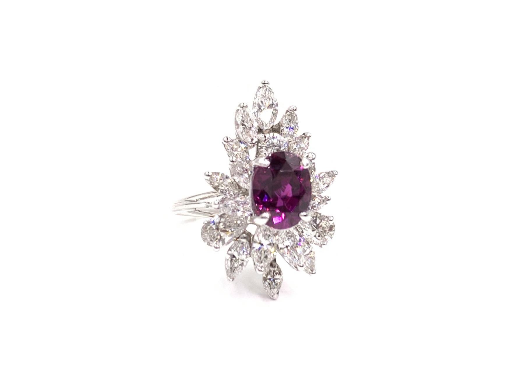 A truly exquisite vintage find. This 14 karat white gold cocktail ring features a vibrant 3.14 carat oval merlot colored ruby surrounded by approximately 4.06 carats of high quality marquise, pear and round diamonds. Diamonds have a generous amount